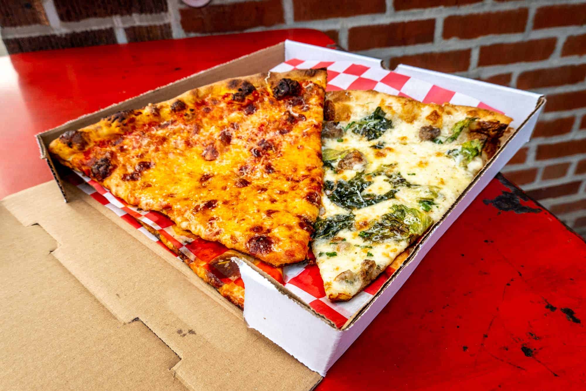 Cheese pizza slice and a white pizza slice in a white cardboard box