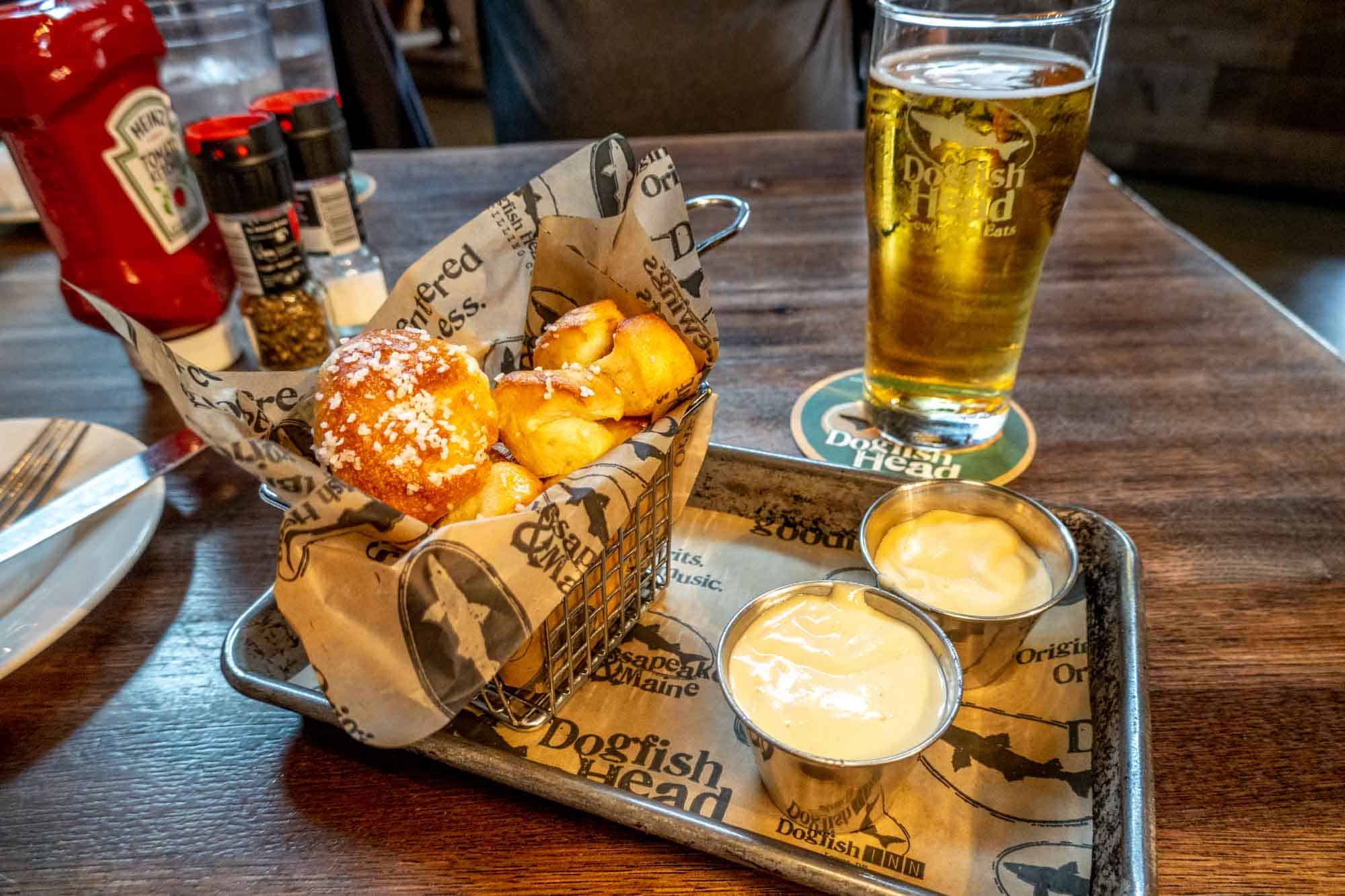 Pint of Dogfish Head beer and basket of pretzel bites on a table