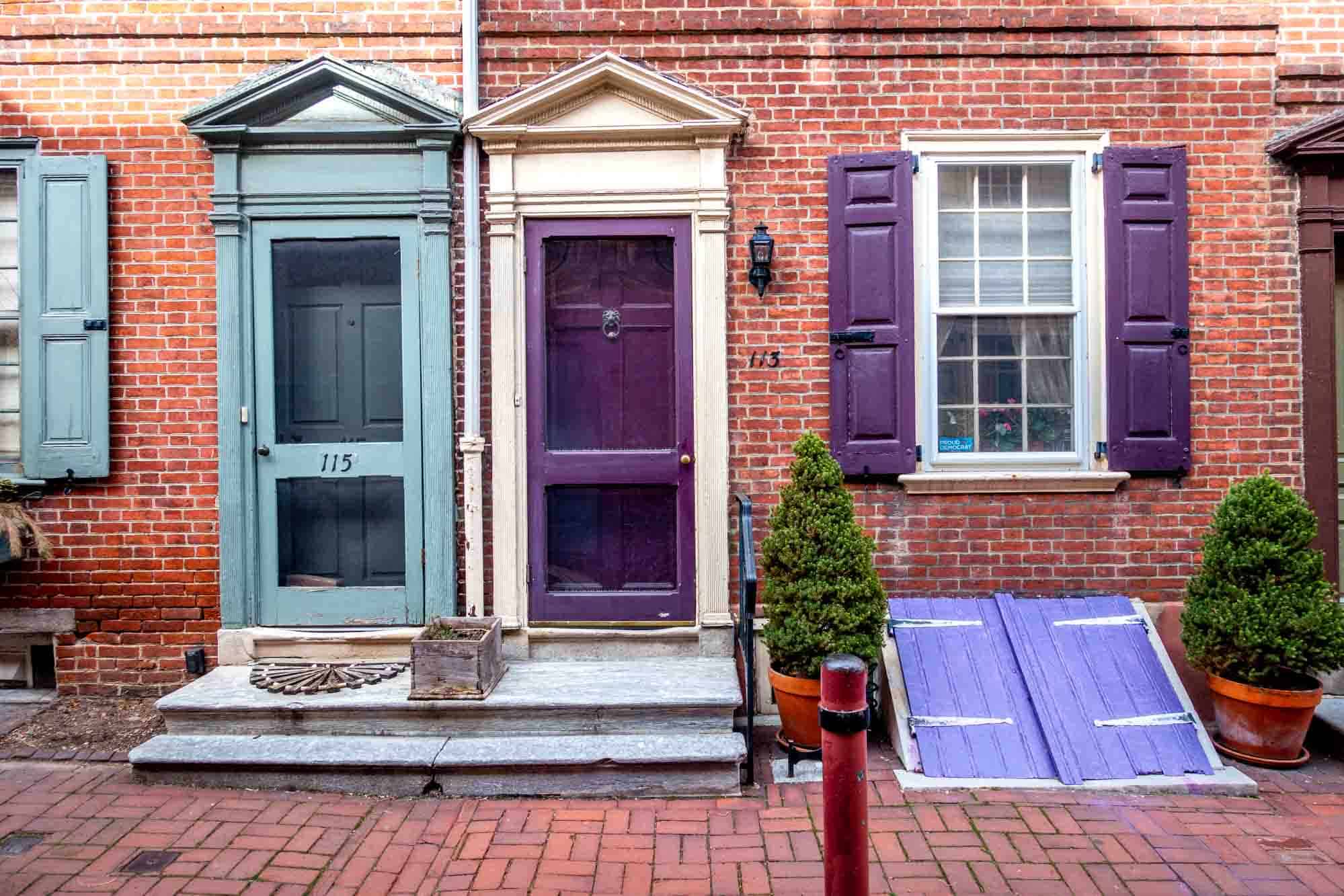 Brightly colored doors and window shutters on brick buildings.