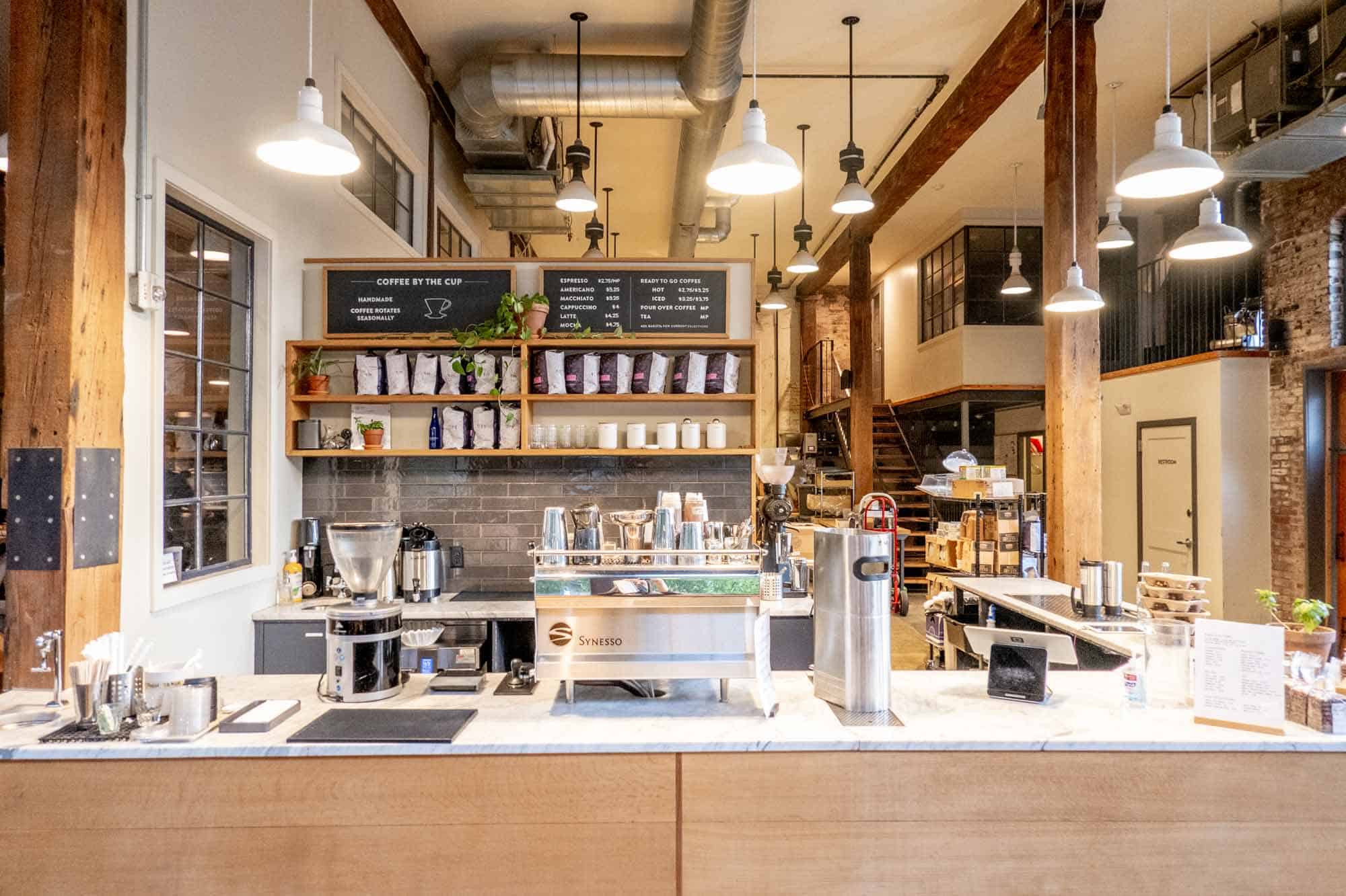 Coffee counter with espresso makers, dishes, and bags of coffee at ReAnimator Coffee 