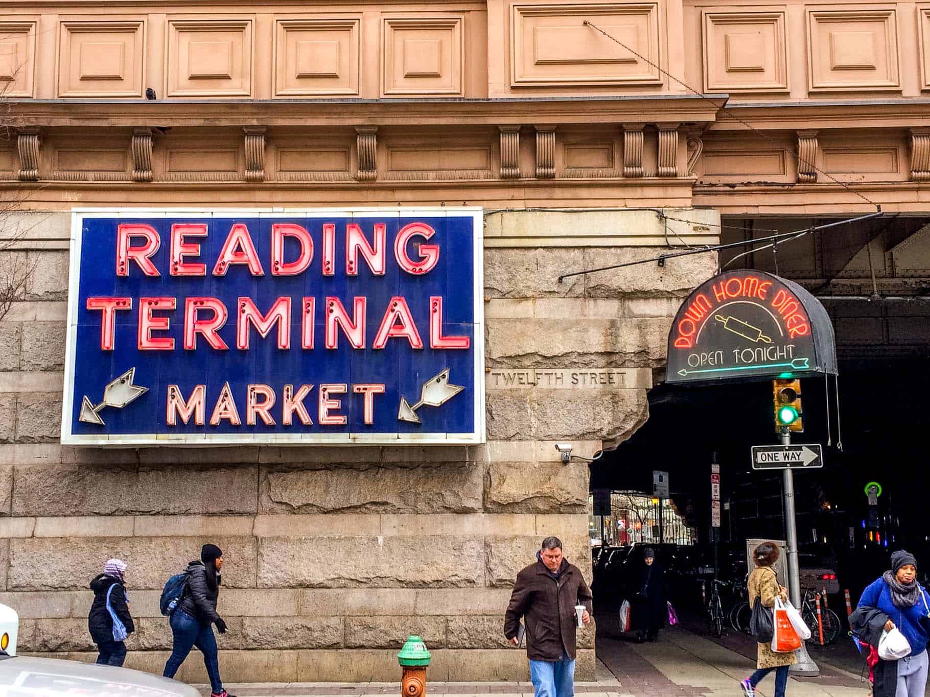 People walking by sign for "Reading Terminal Market." 