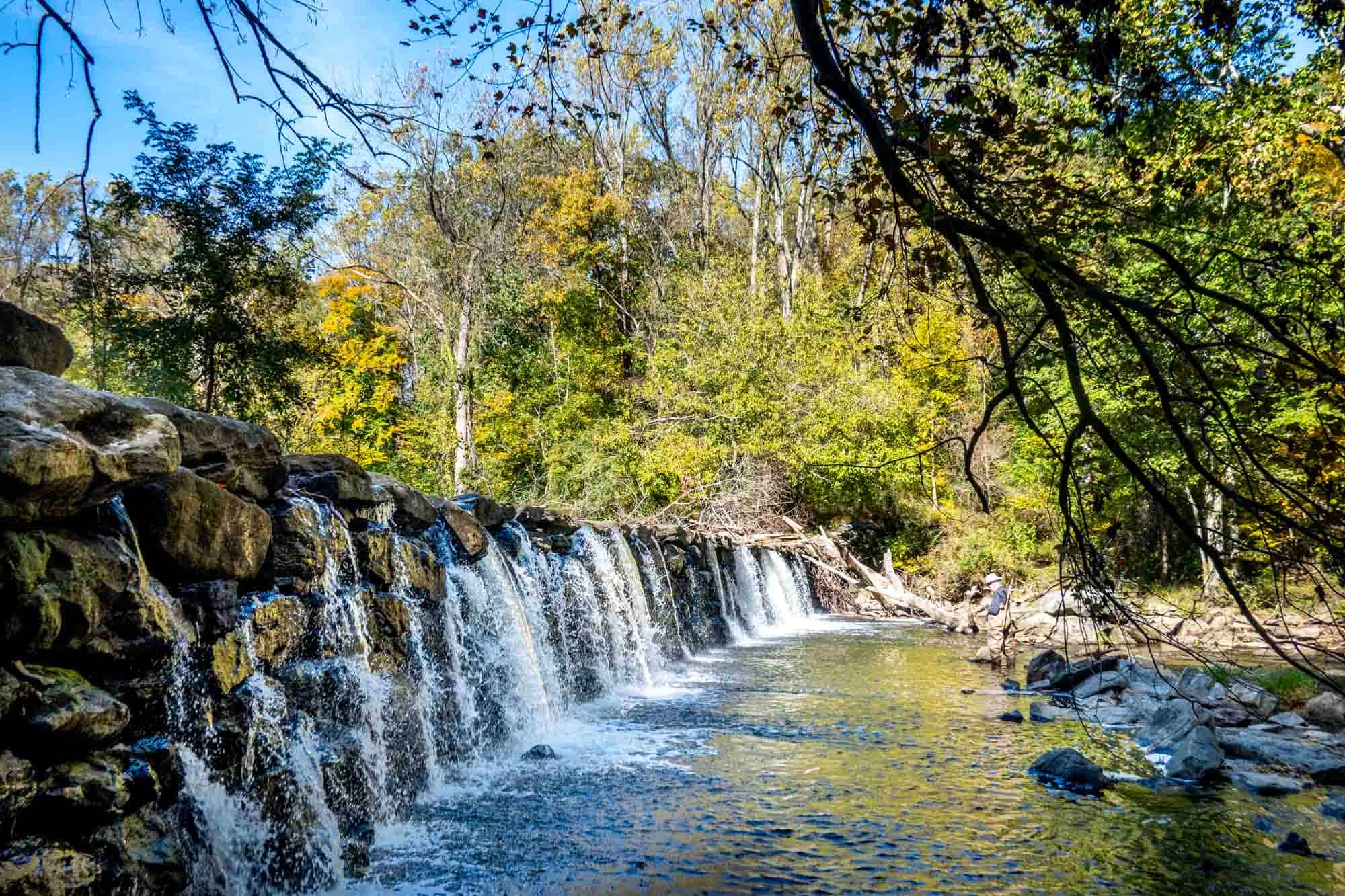 Fisherman in creek with waterfall