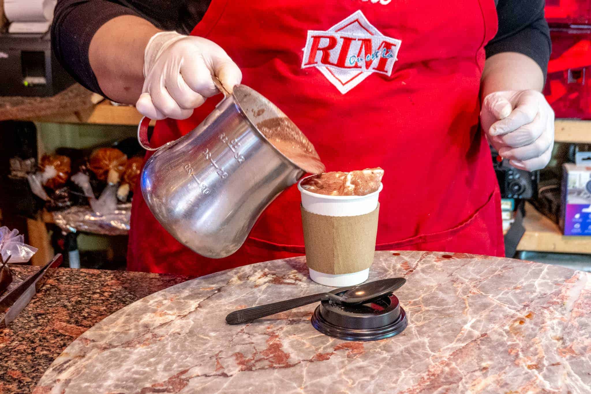 Woman pouring hot chocolate from a pitcher into a cup
