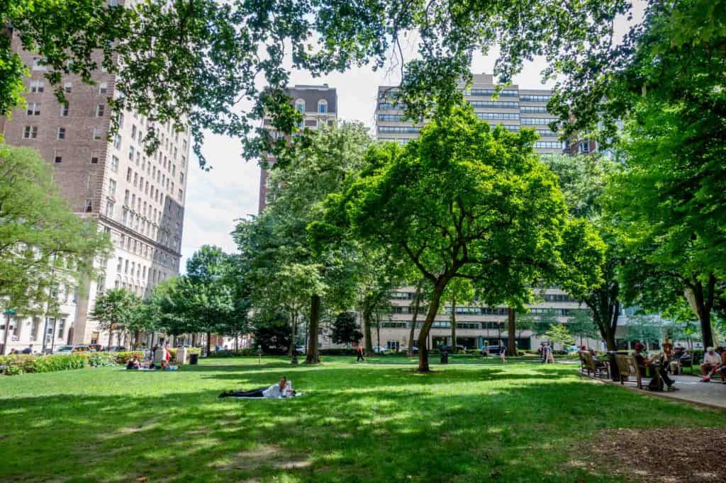 People in tree-filled Rittenhouse Square park on a sunny day
