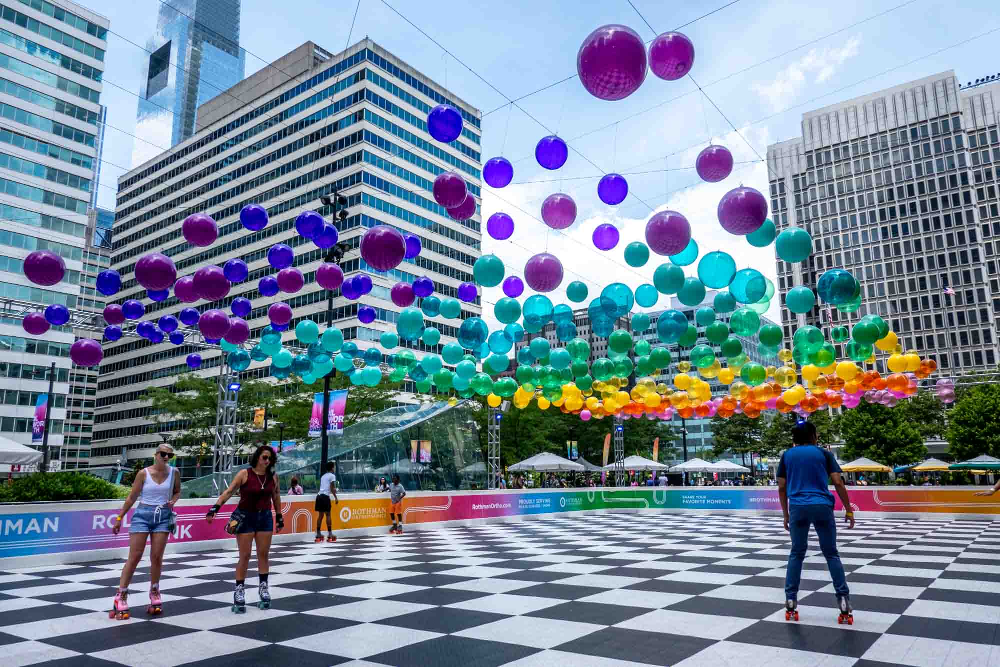 People roller skating underneath a canopy of colorful balls.