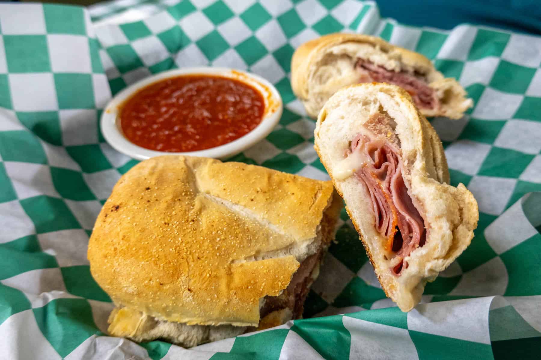 Stromboli sandwich cut open with red dipping sauce