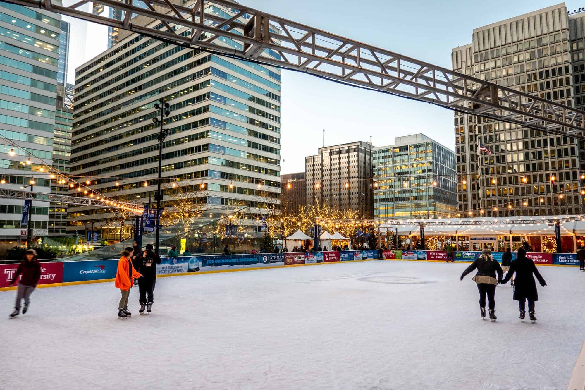 People skating on an ice-skating rink surrounded by high-rise buildings