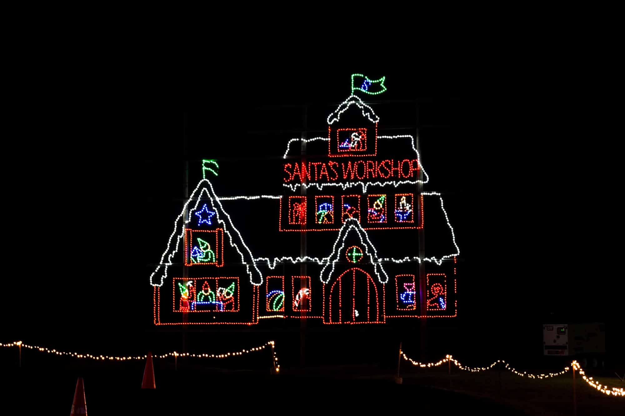 Christmas light display in the shape of a house with a sign for "Santa's Workshop."