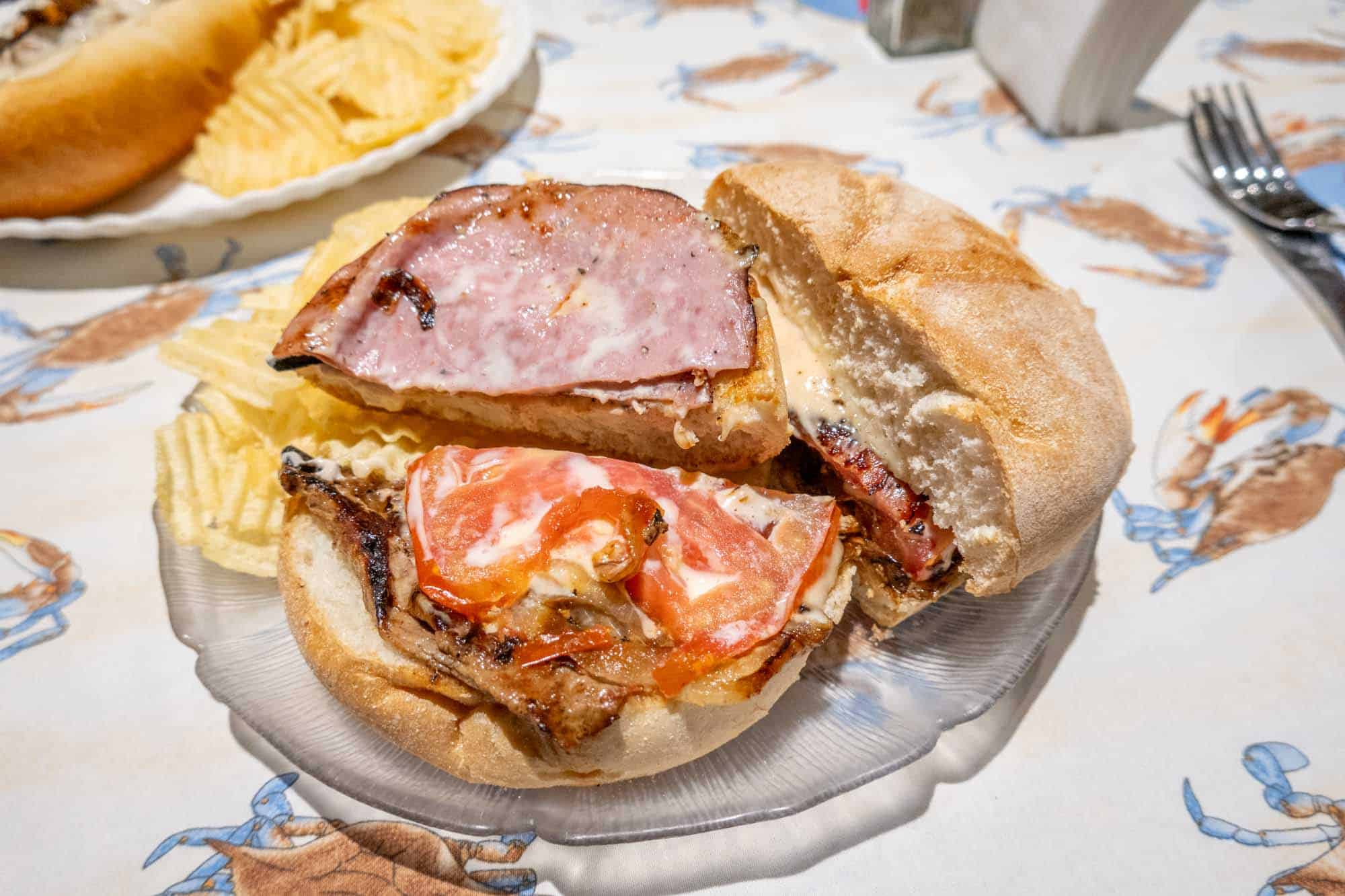 Sandwich opened to reveal fried onions, tomatoes and gooey sauce