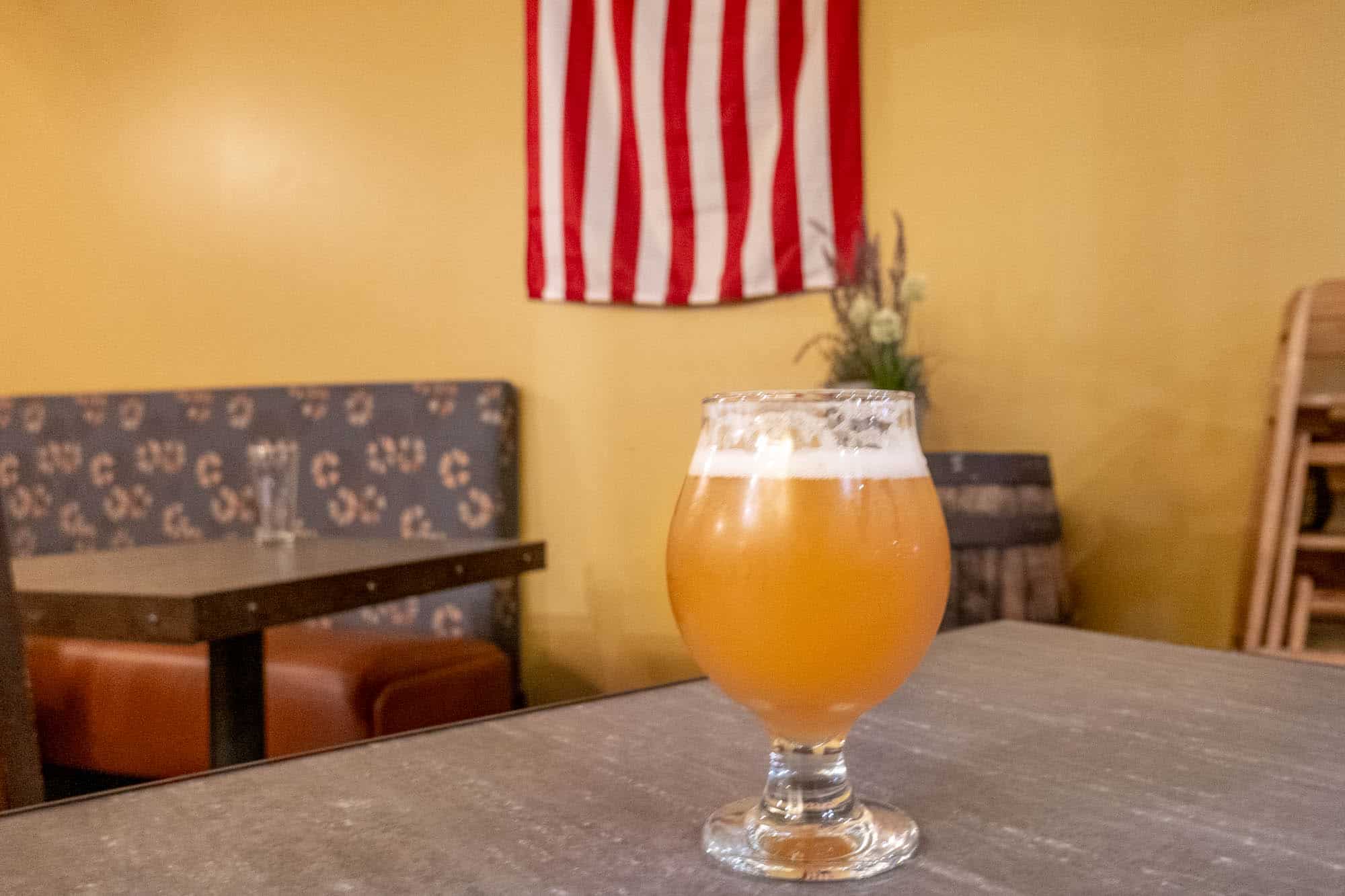 Glass of beer on table with American flag in background
