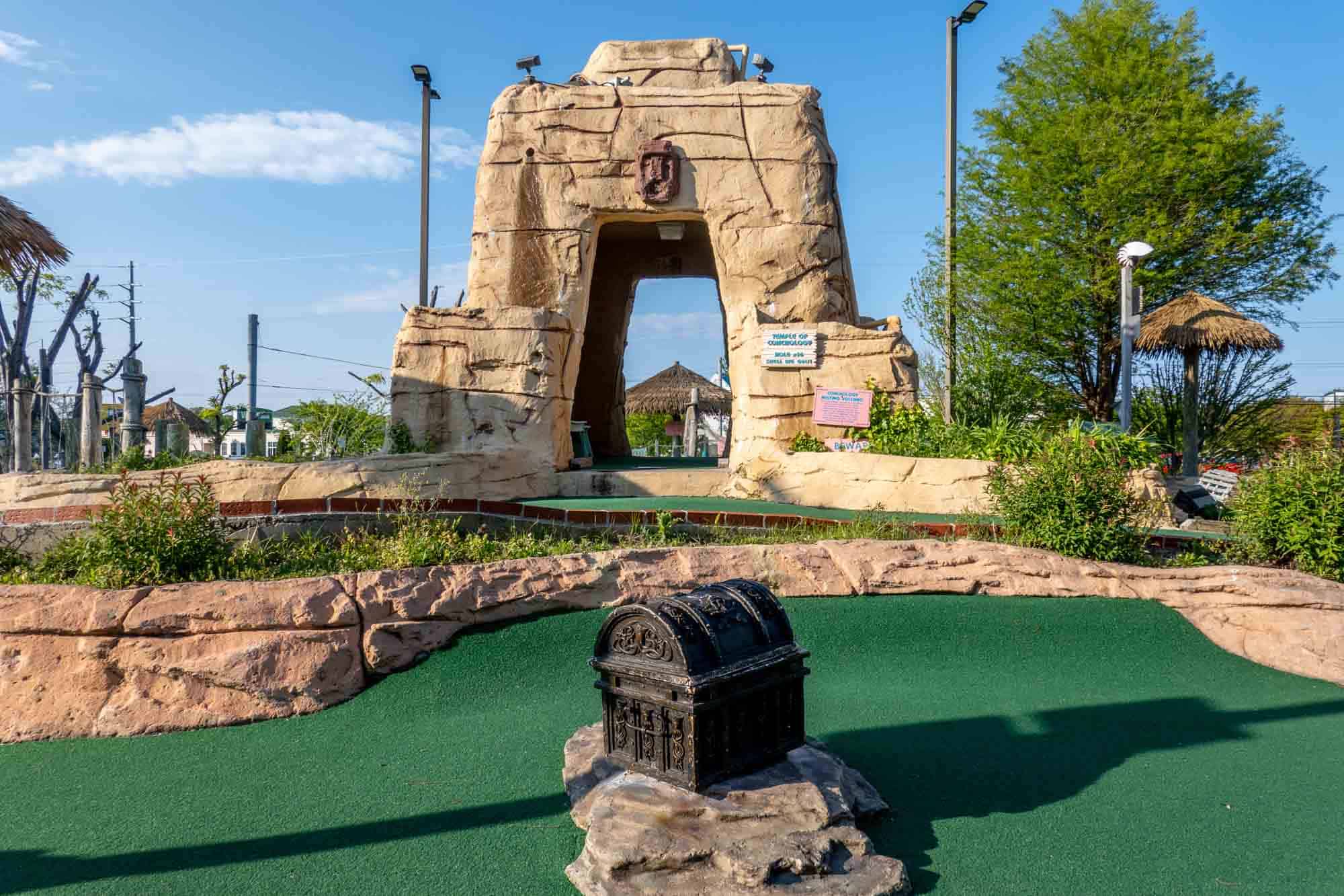 Hole on a mini-golf course including a fake treasure chest.