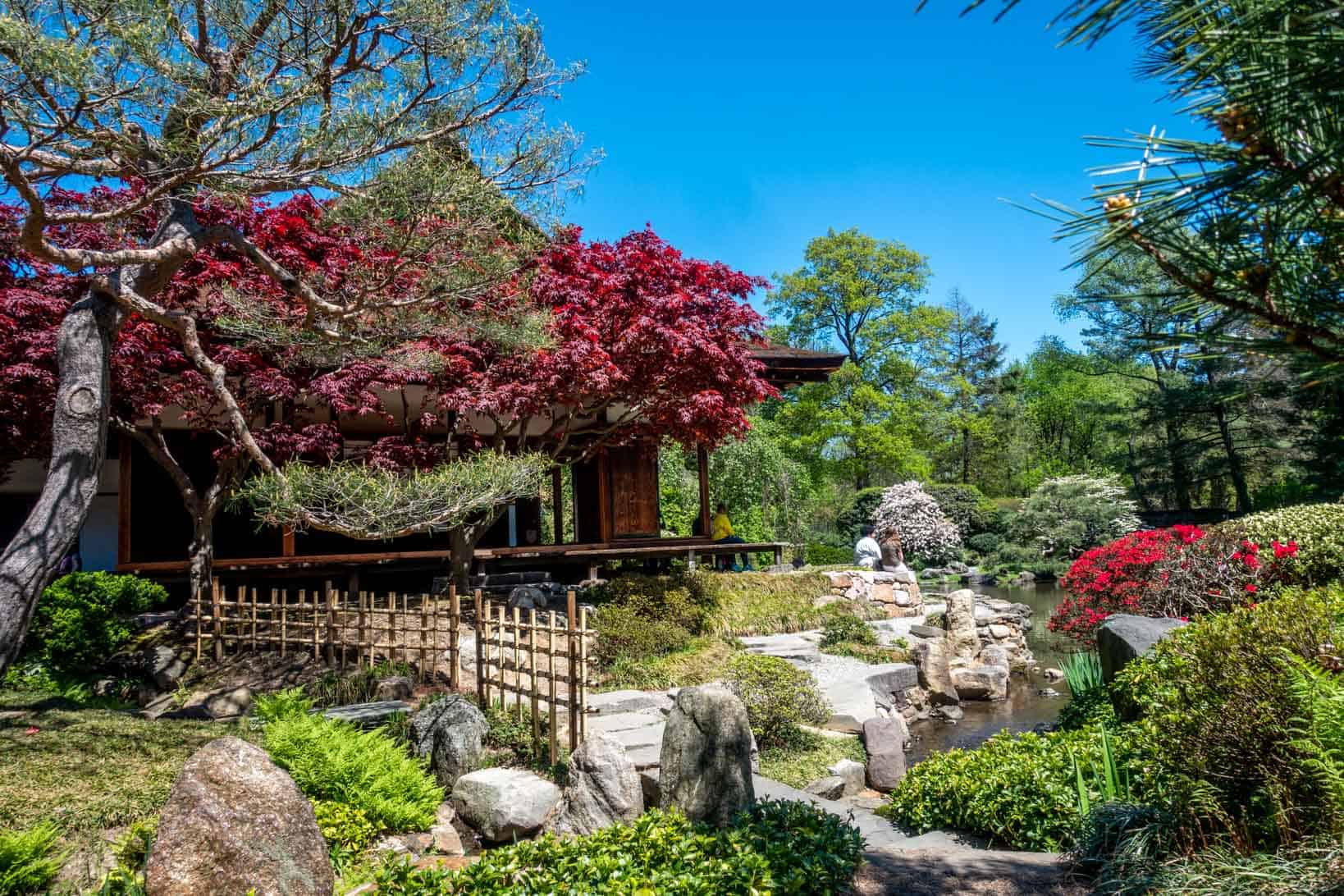 Bridge in front of a Japanese house surrounded by a pond and garden.