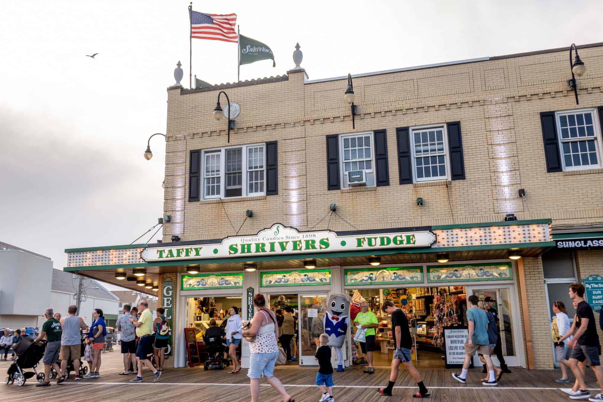 Exterior of a corner store with a sign: "Taffy Shrivers Fudge."