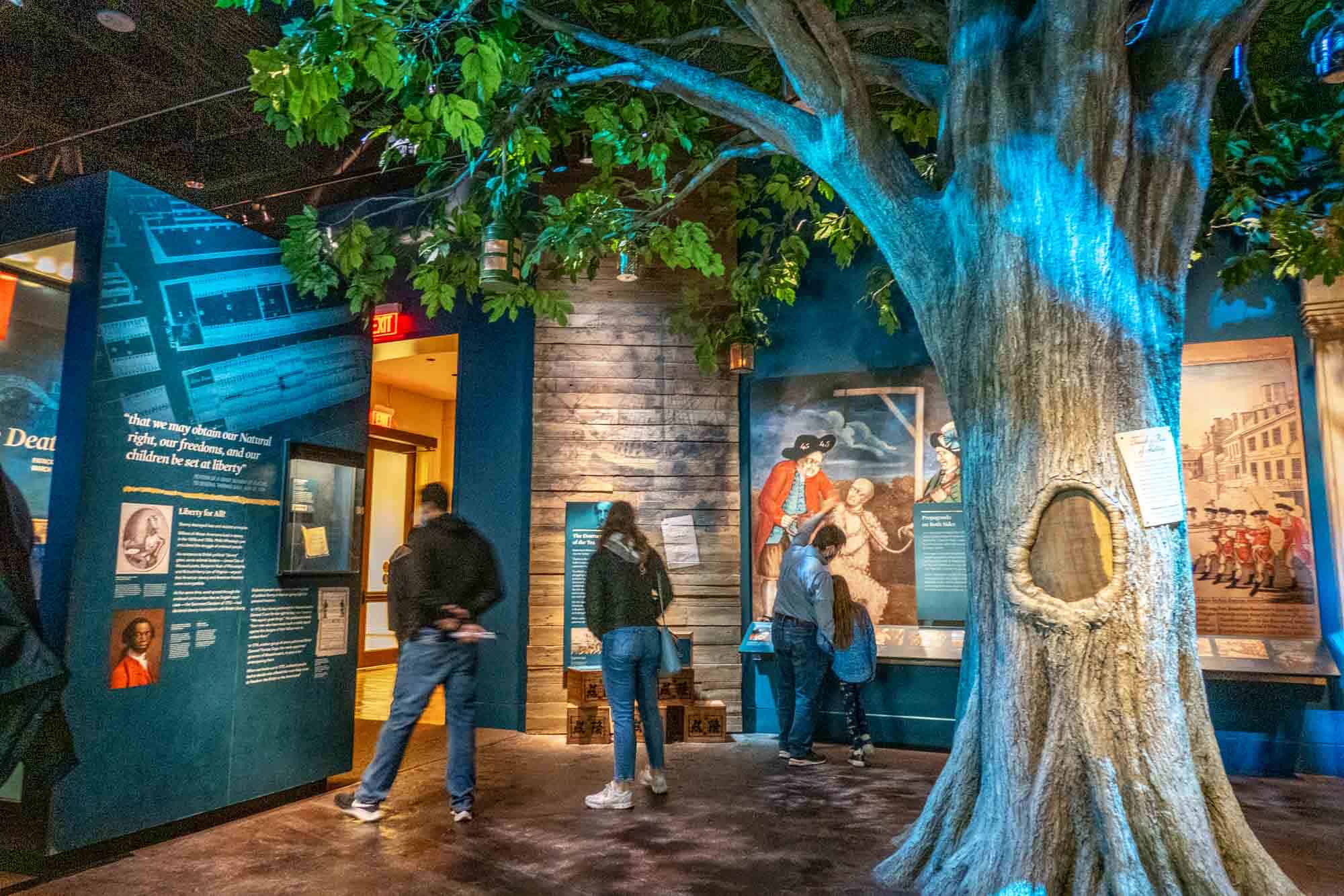 People looking at panels in a museum with a fake tree in the foreground
