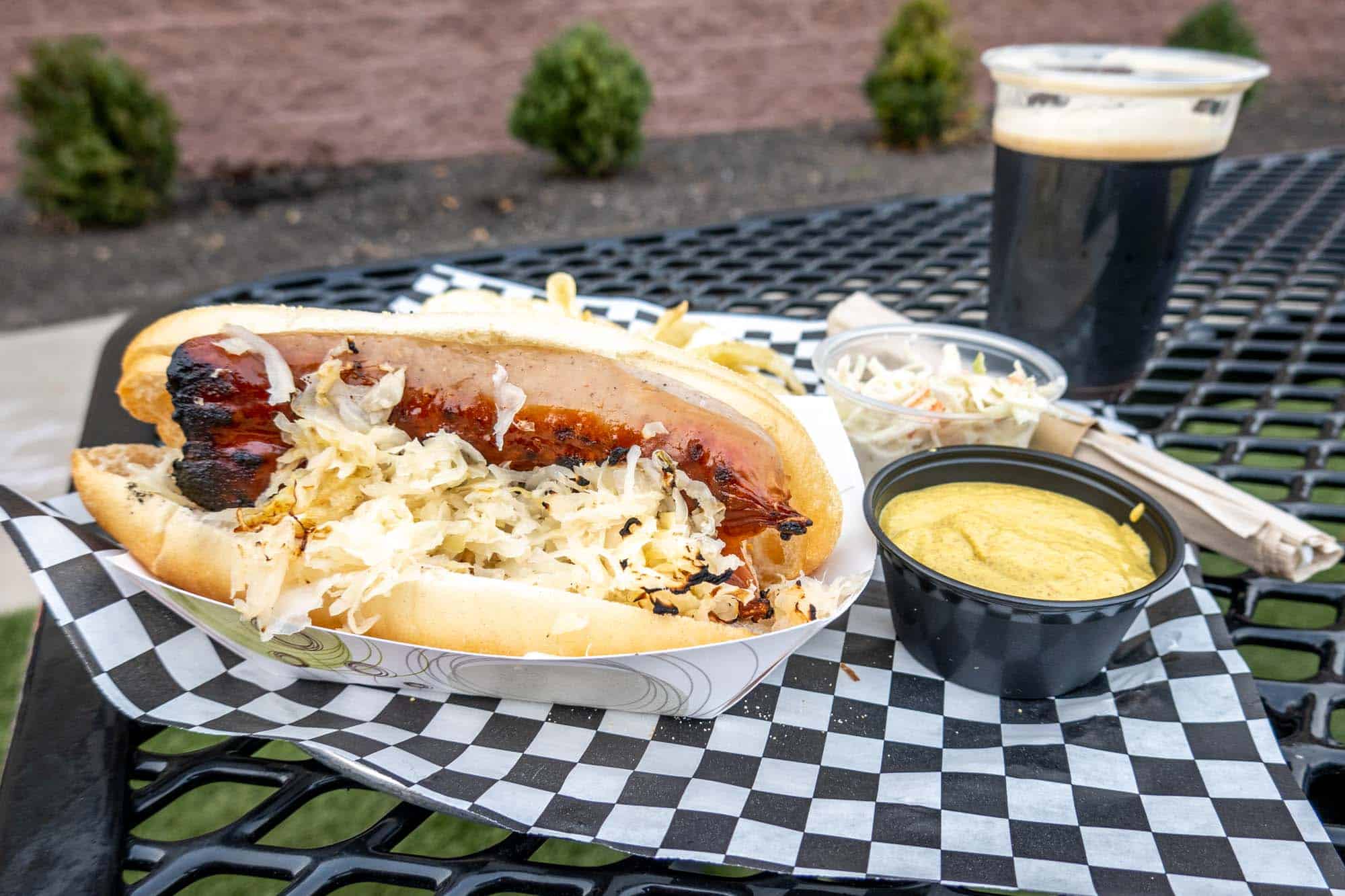 Bratwurst and sauerkraut sandwich on a table with a beer