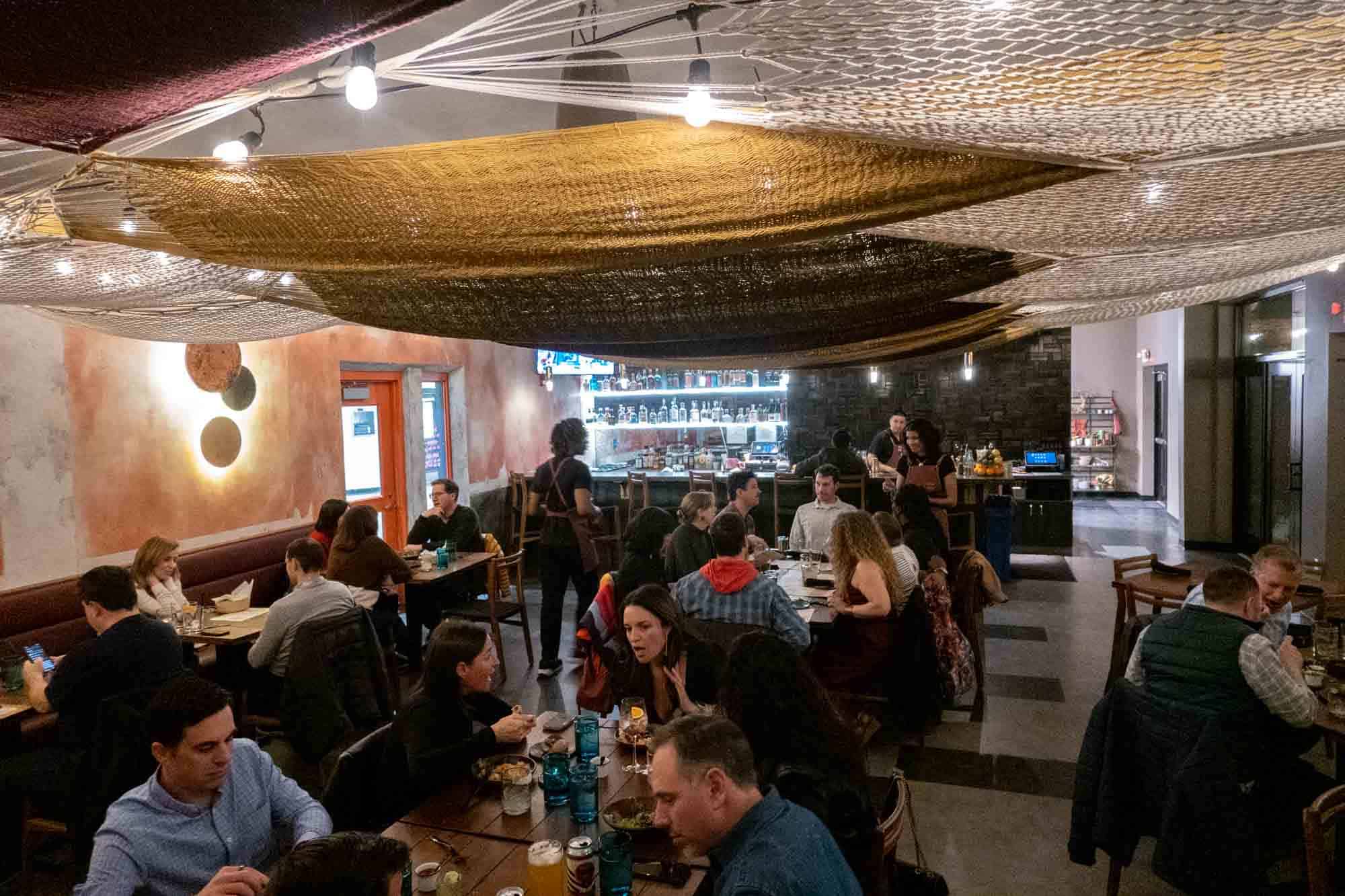 People eating dinner in restaurant under hammocks hung from the ceiling