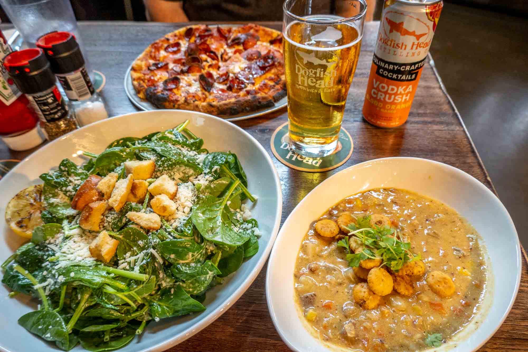 Soup, salad, pizza, and drinks on a table at Dogfish Head Brewing 