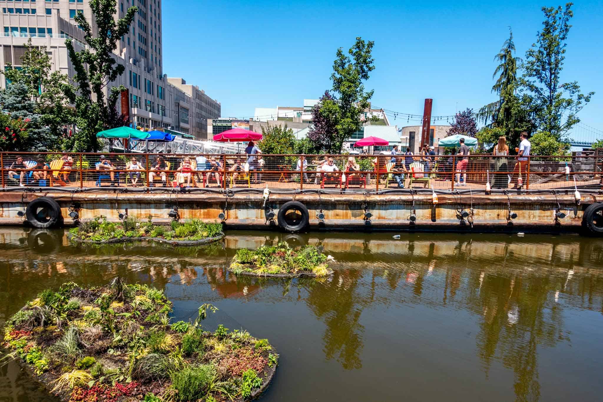 Floating gardens and people sitting on floating platform in Delaware River