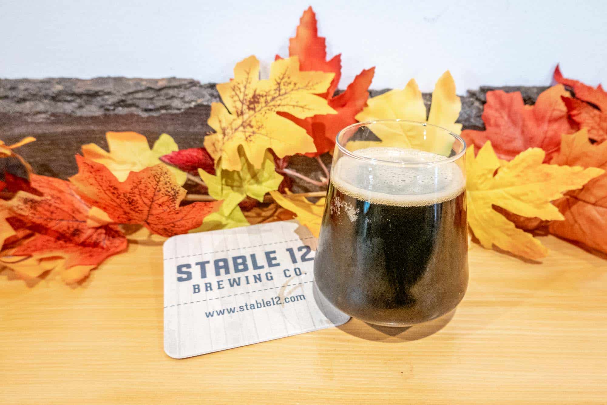 Glass of beer on decorated table with coaster that says Stable 12 Brewing Co