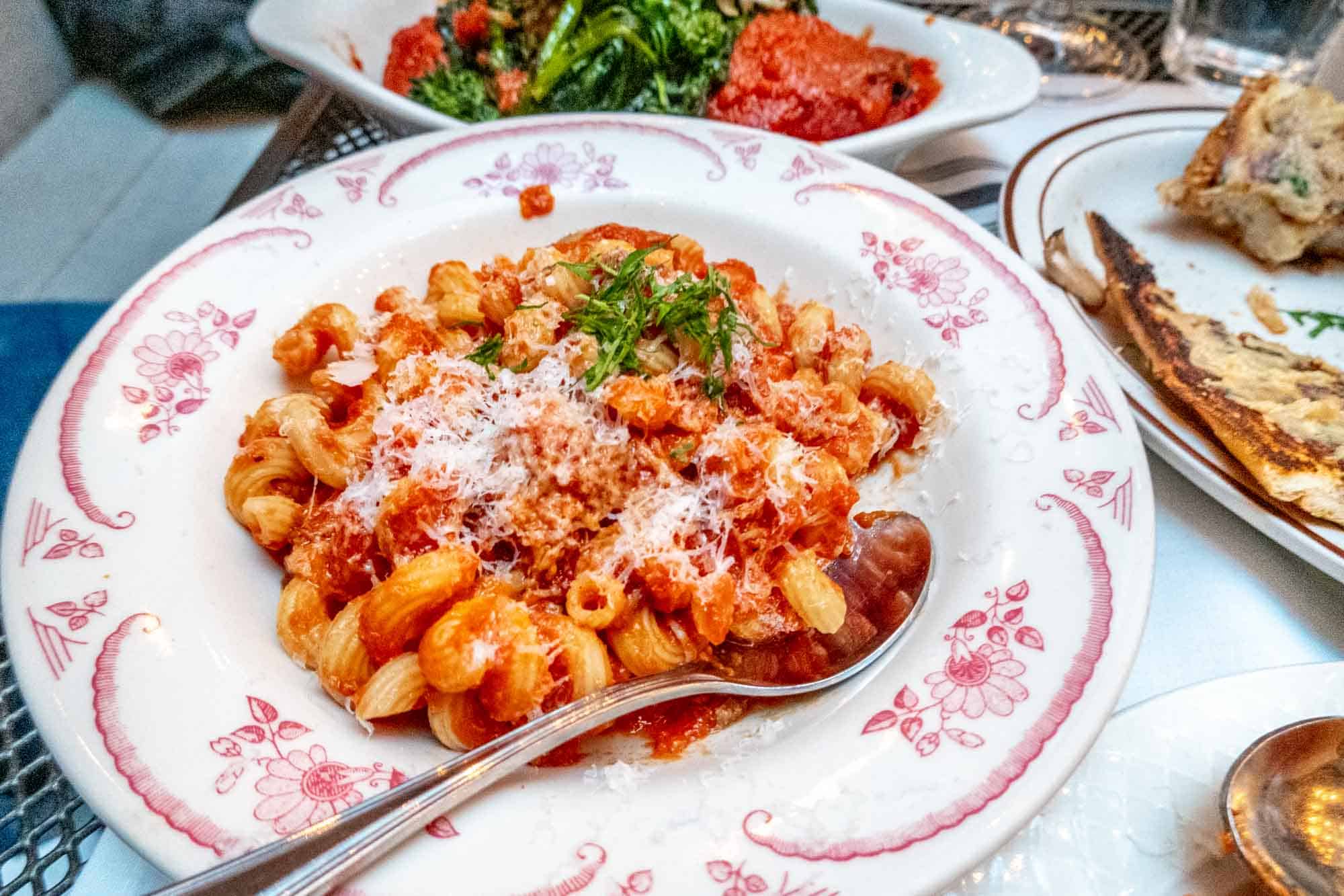 Macaroni and marinara sauce in a bowl beside other Italian dishes