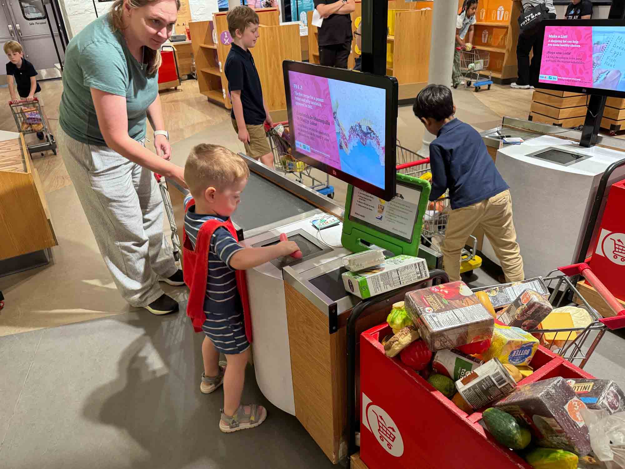 Parent and child scanning groceries in a kids' museum.