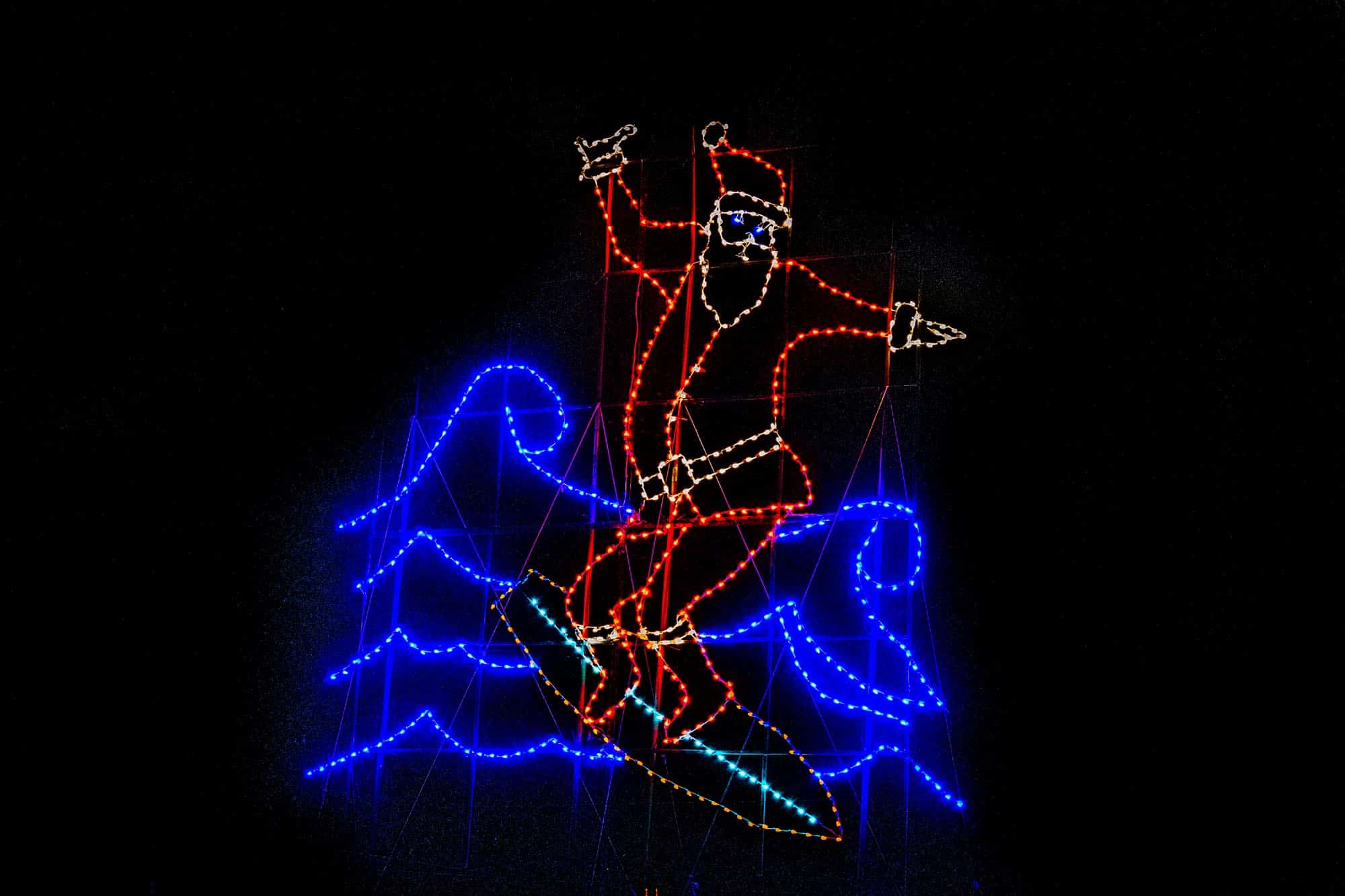 Santa surfing a wave in Christmas lights