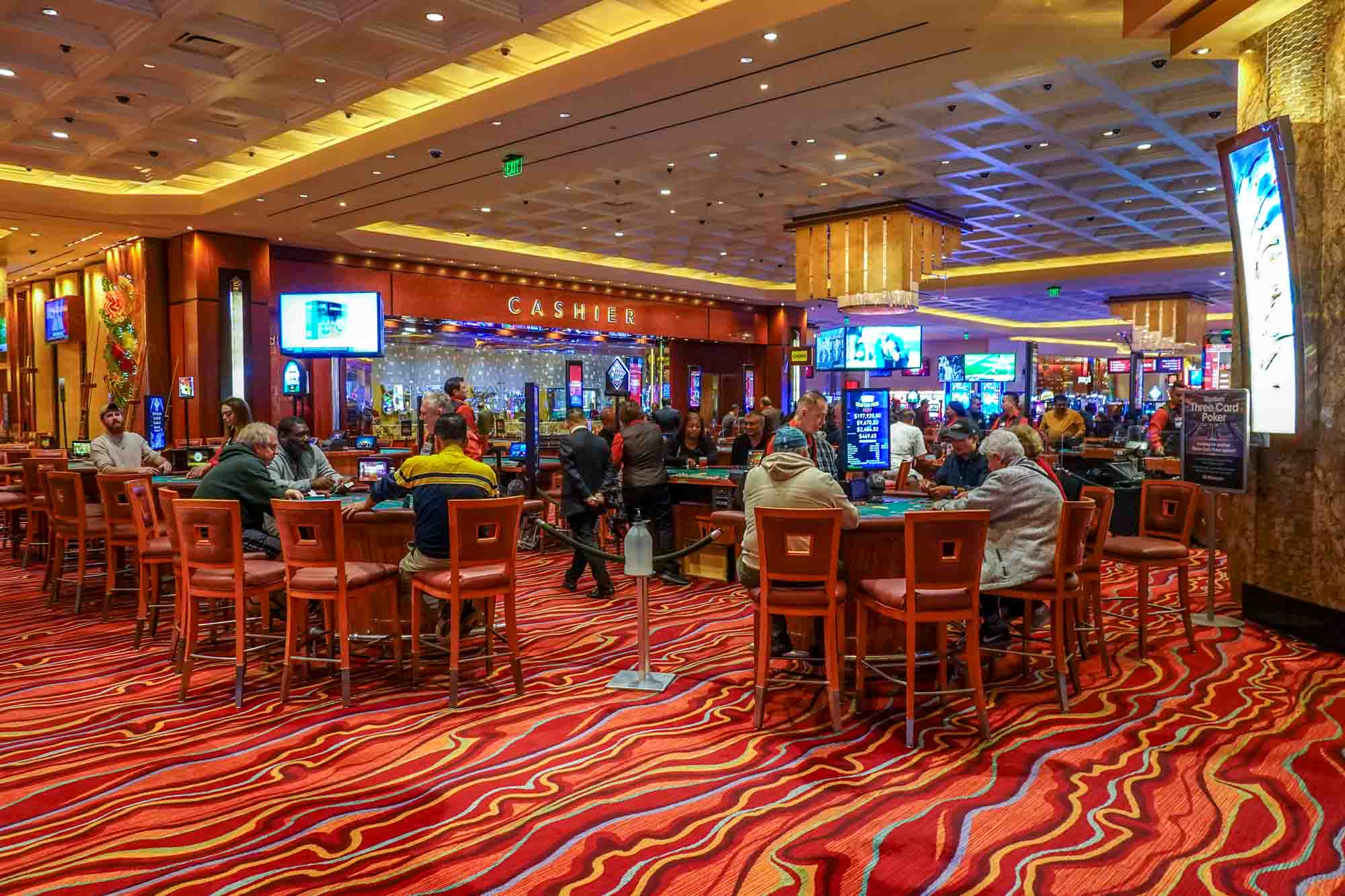 People seated at gaming tables in a casino.