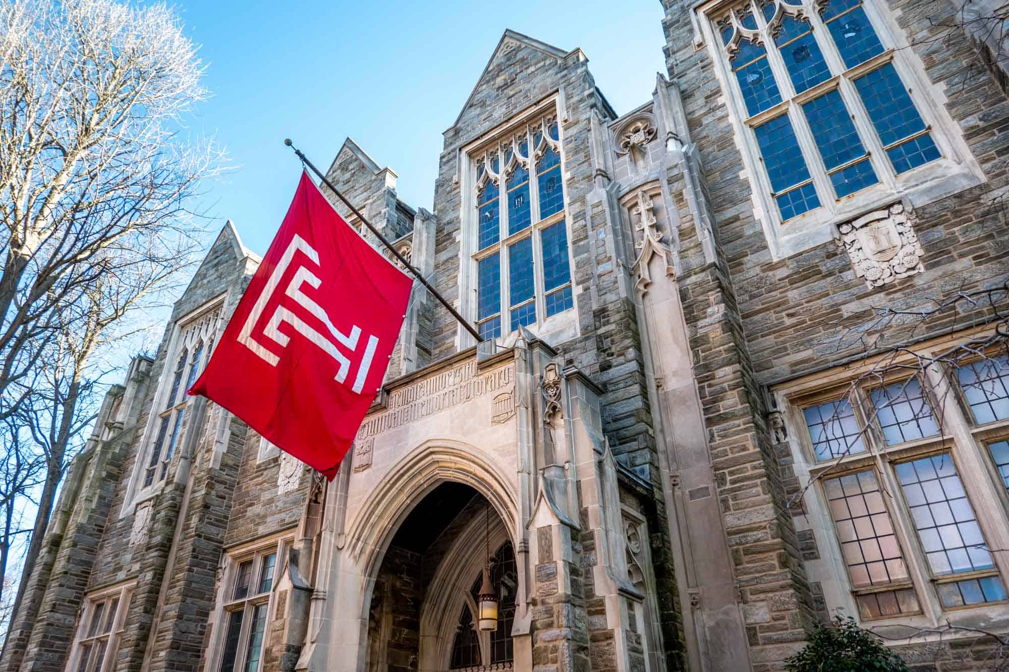 Red Temple University flag in front of building