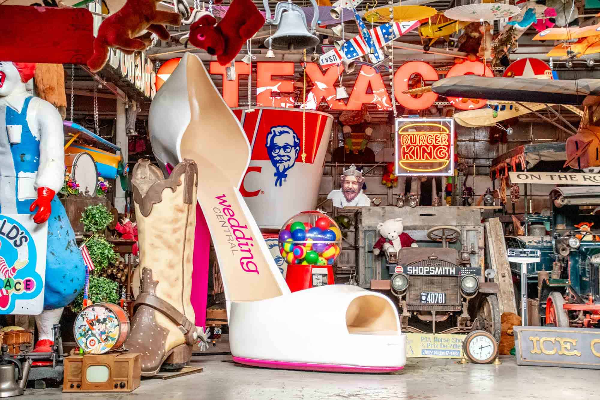 Texaco and Burger King neon signs displayed beside a giant high-heeled shoe and lots of other eclectic items