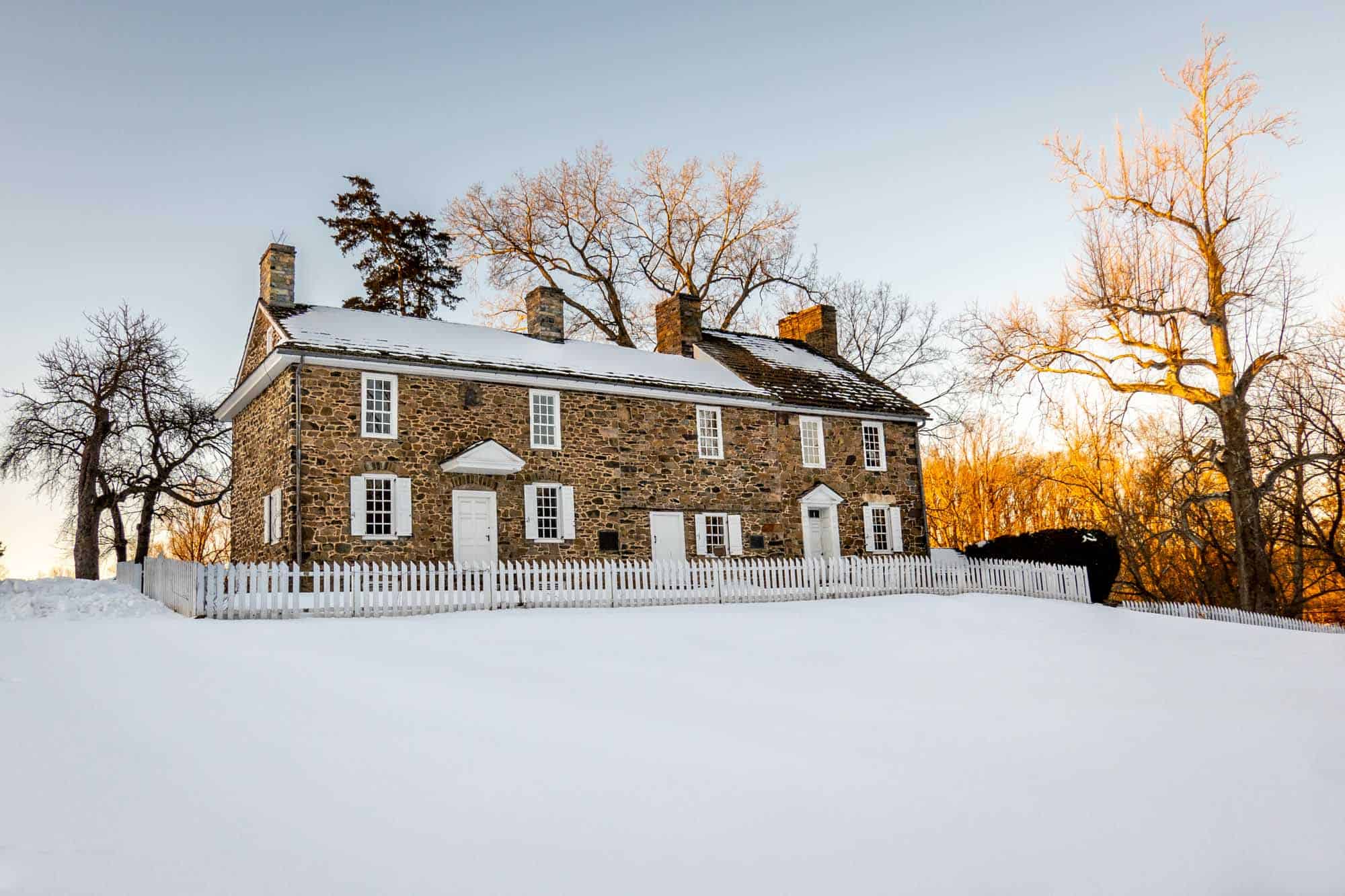 Exterior of a colonial stone building on a snowy day.