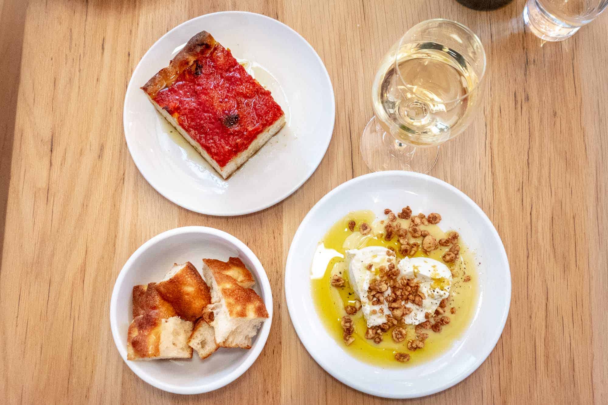 Burrata in olive oil with burrata and tomato pie appetizers with glass of white wine