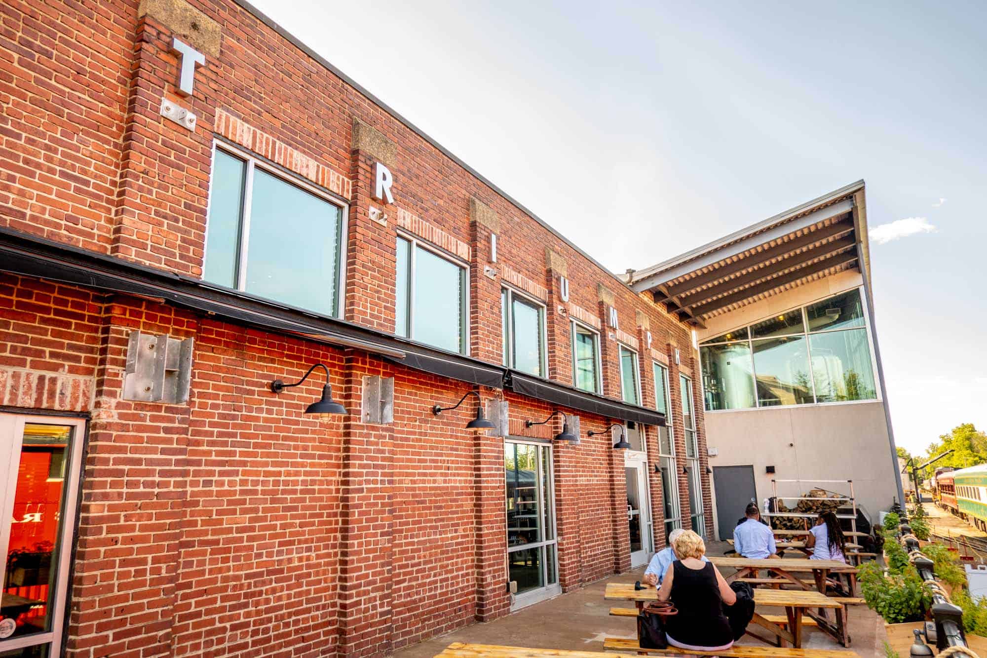 People at picnic tables on patio at Triumph brewery