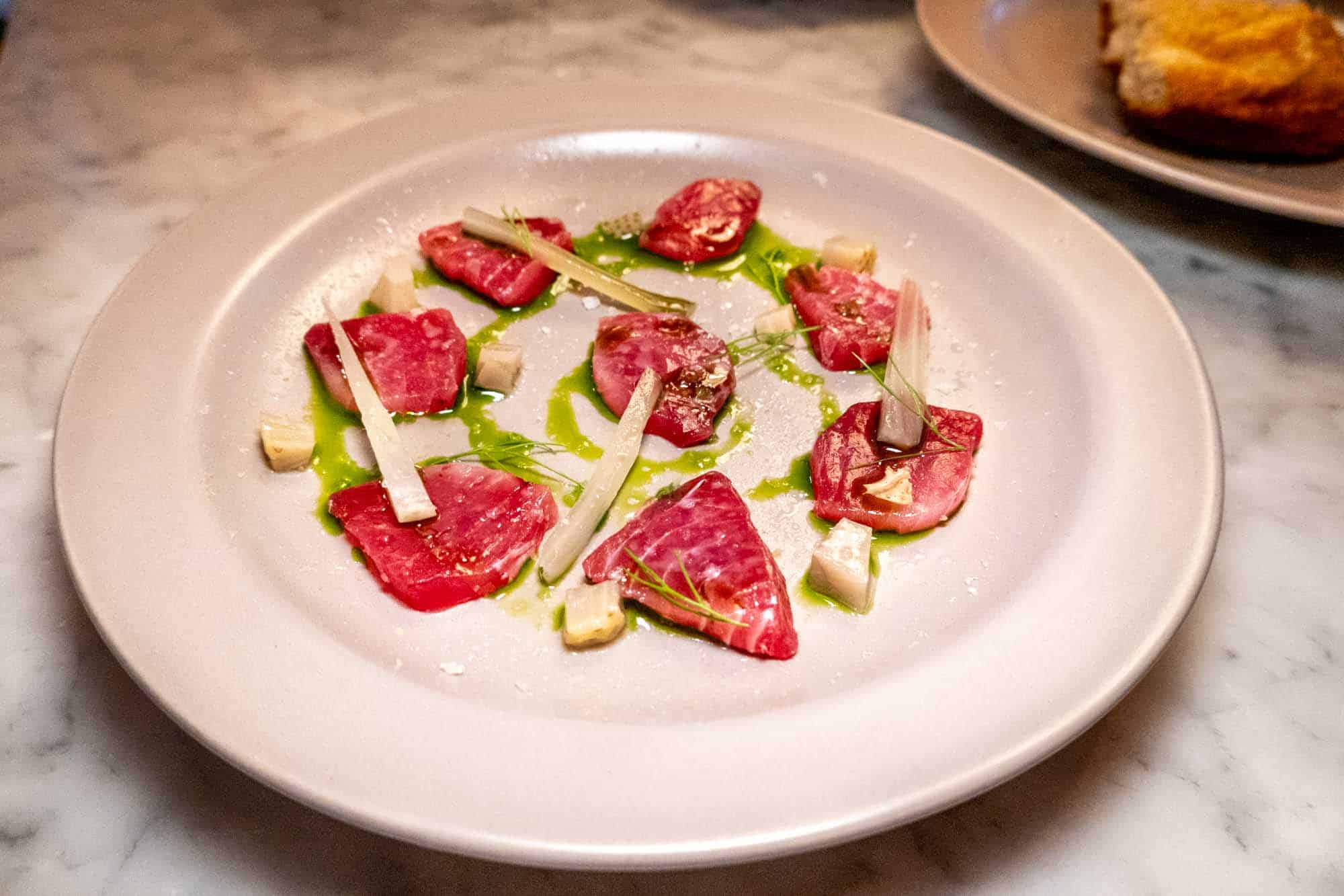 Slices of tuna crudo on plate