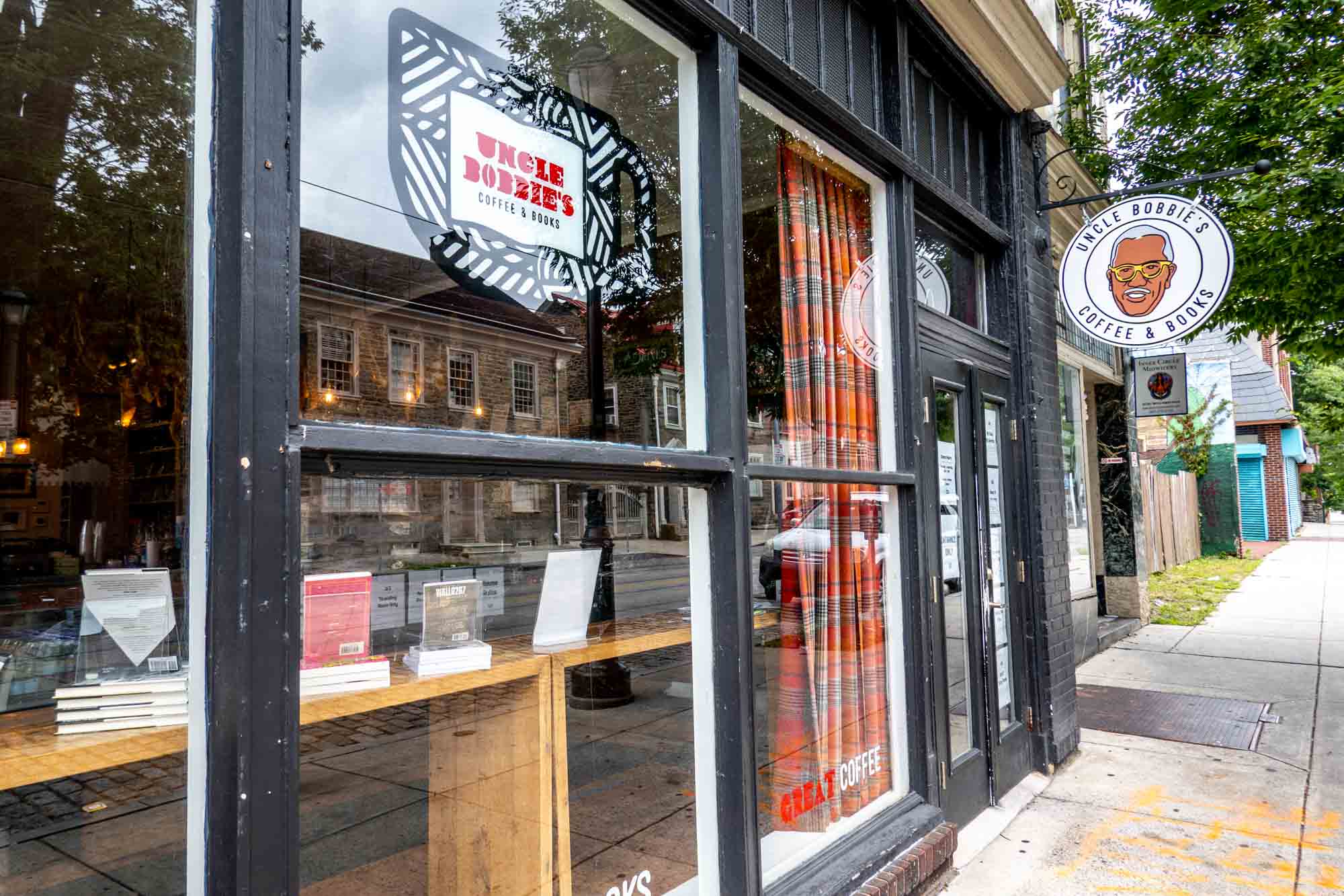 Exterior of a storefront with lots of windows and a logo with a man's face labeled "Uncle Bobbie's Coffee & Books."