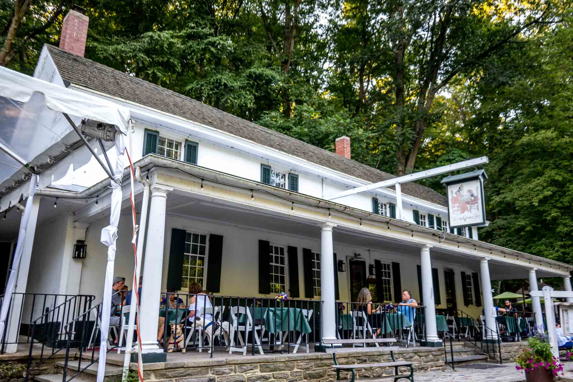 People seated at tables on the patio of an historic inn.