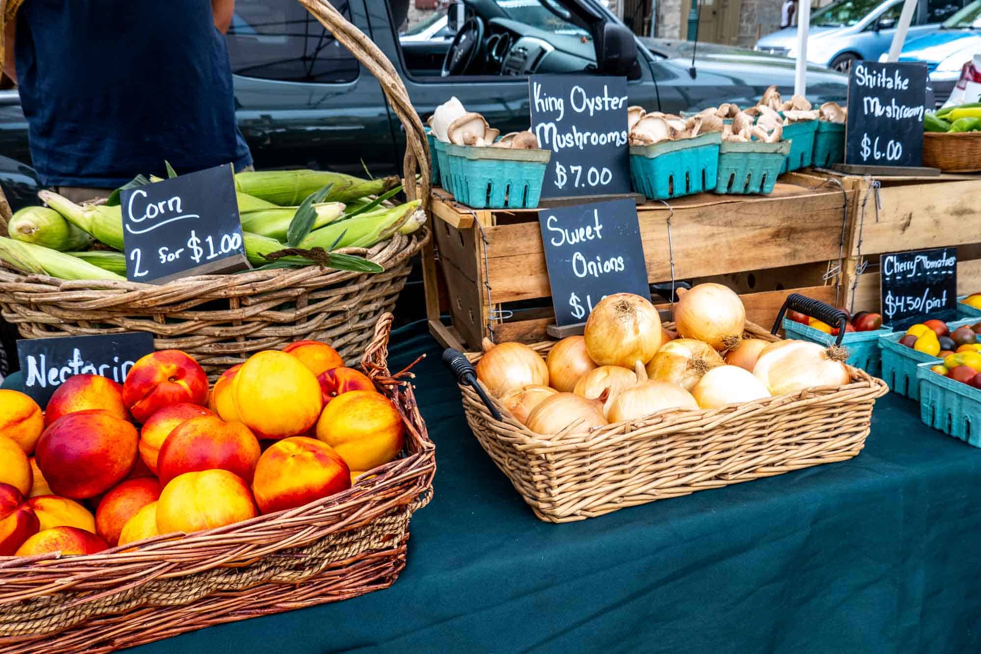 Wicker baskets of nectarines, sweet onions, corn, and mushrooms