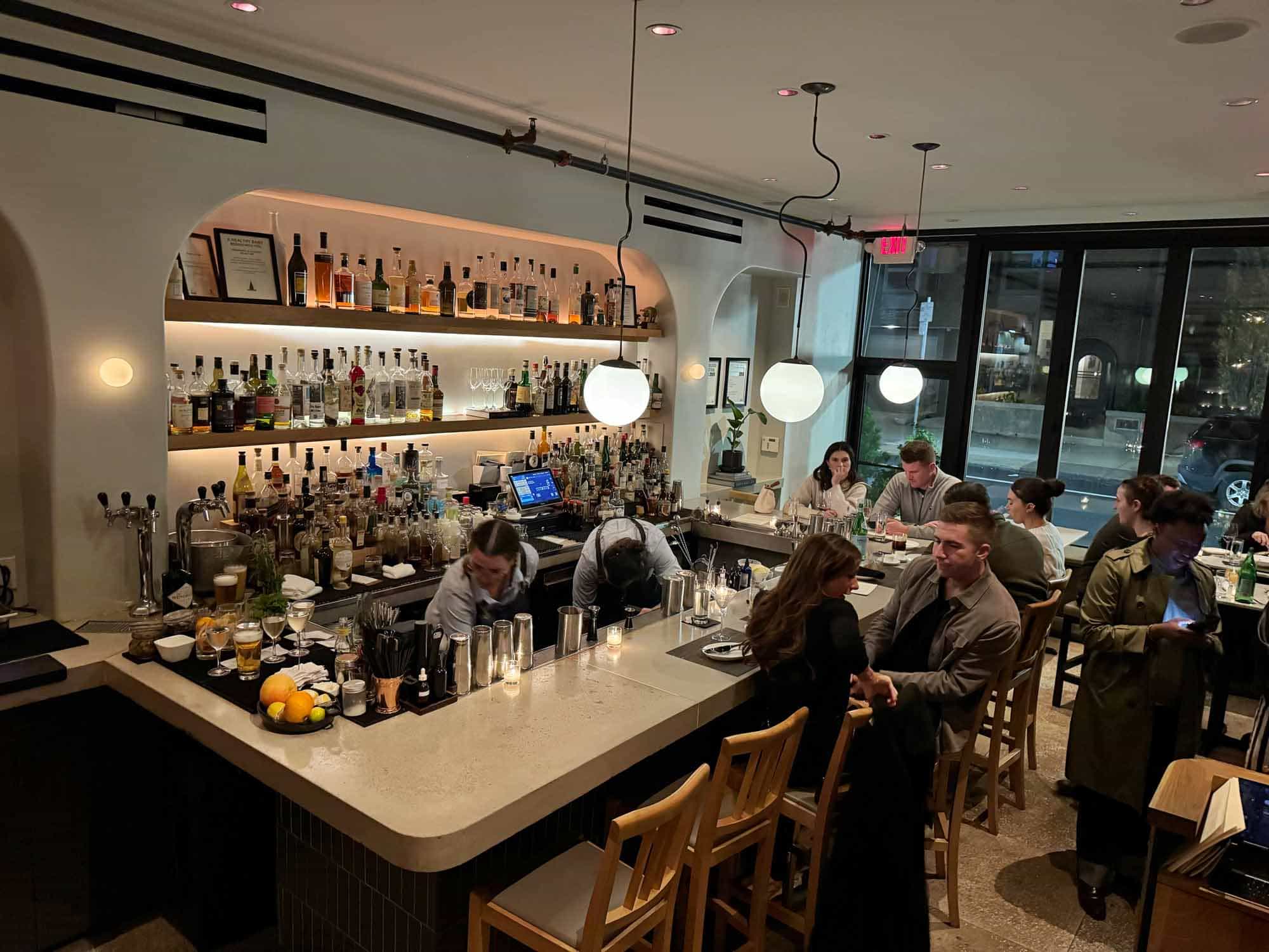 People sitting at a restaurant bar and bartenders working.