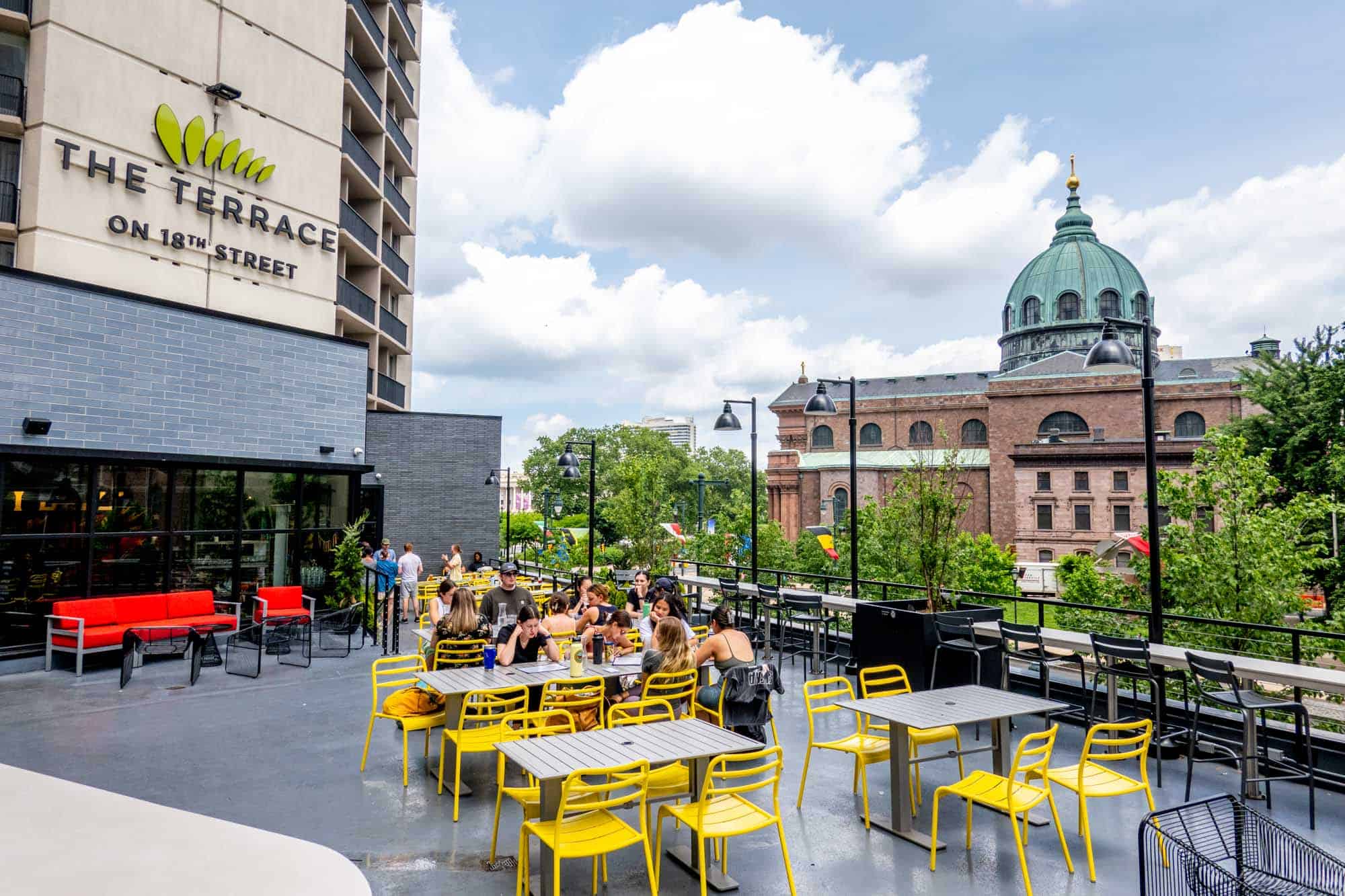 People seated on a roof deck with taller buildings around.