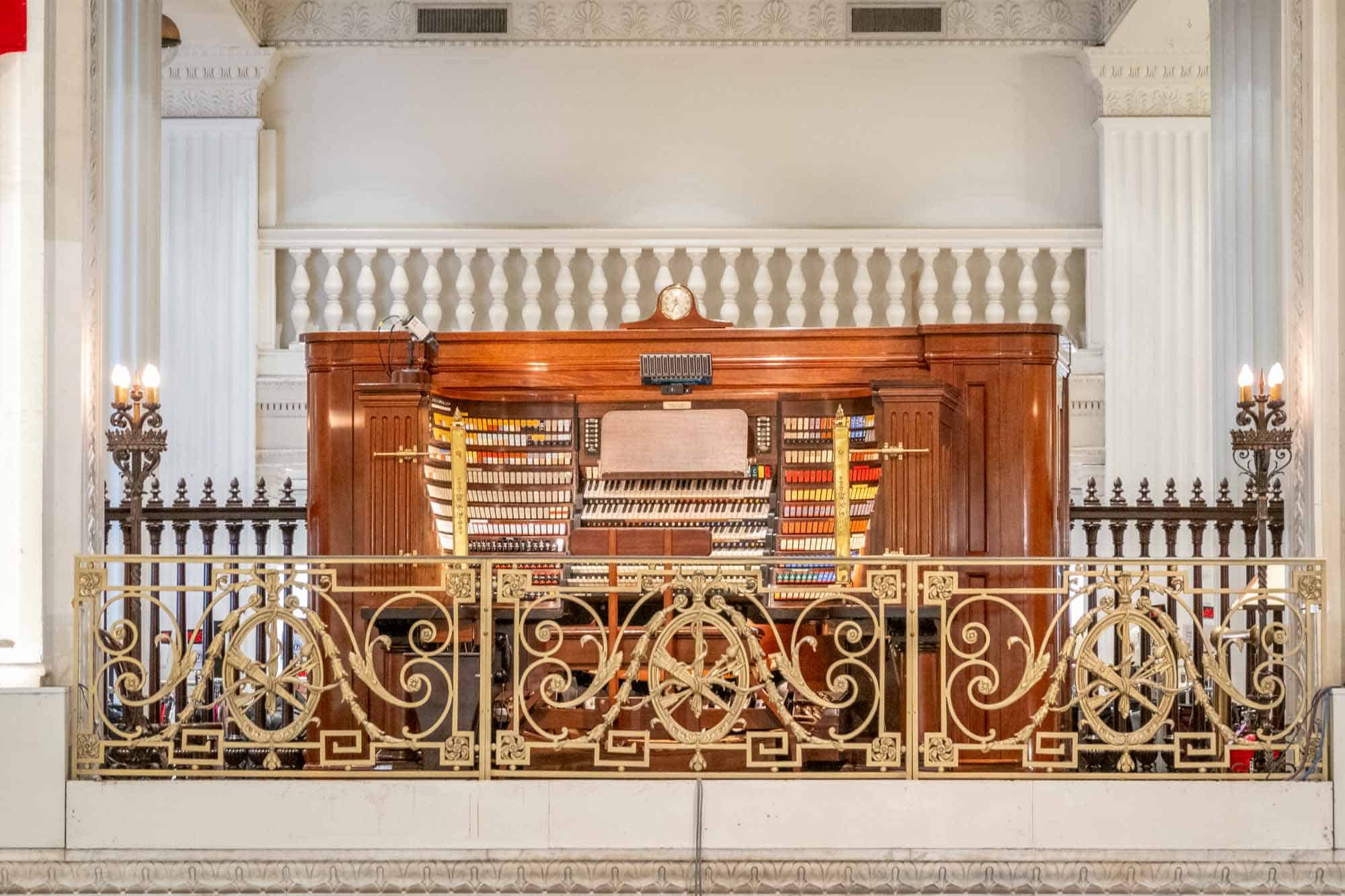 Organ console with colored keys behind a wrought iron railing