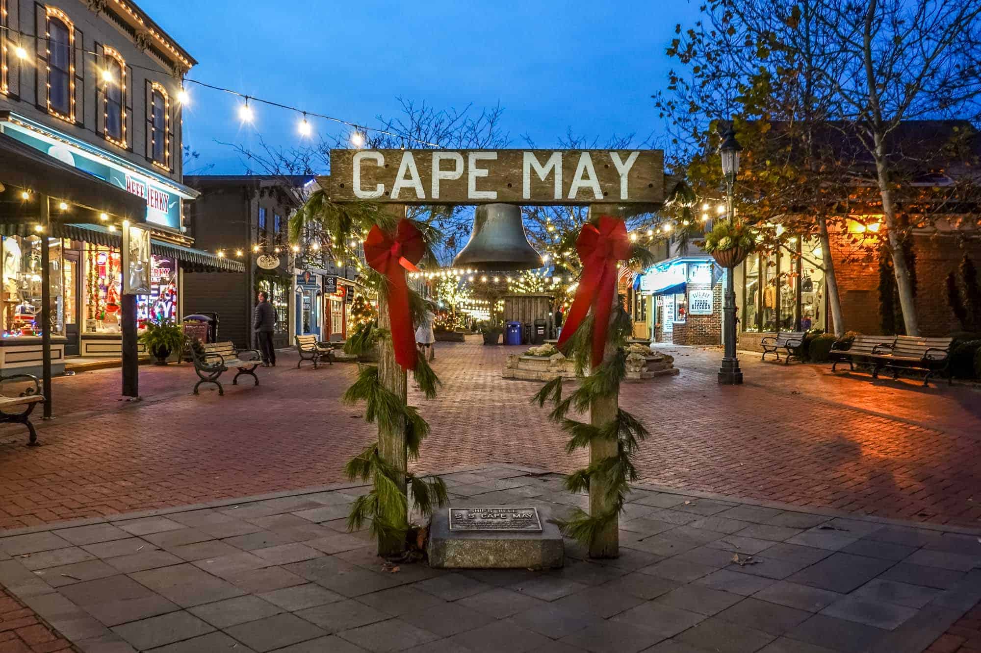Sign for "Cape May" with a bell hanging from it at a pedestrian shopping mall