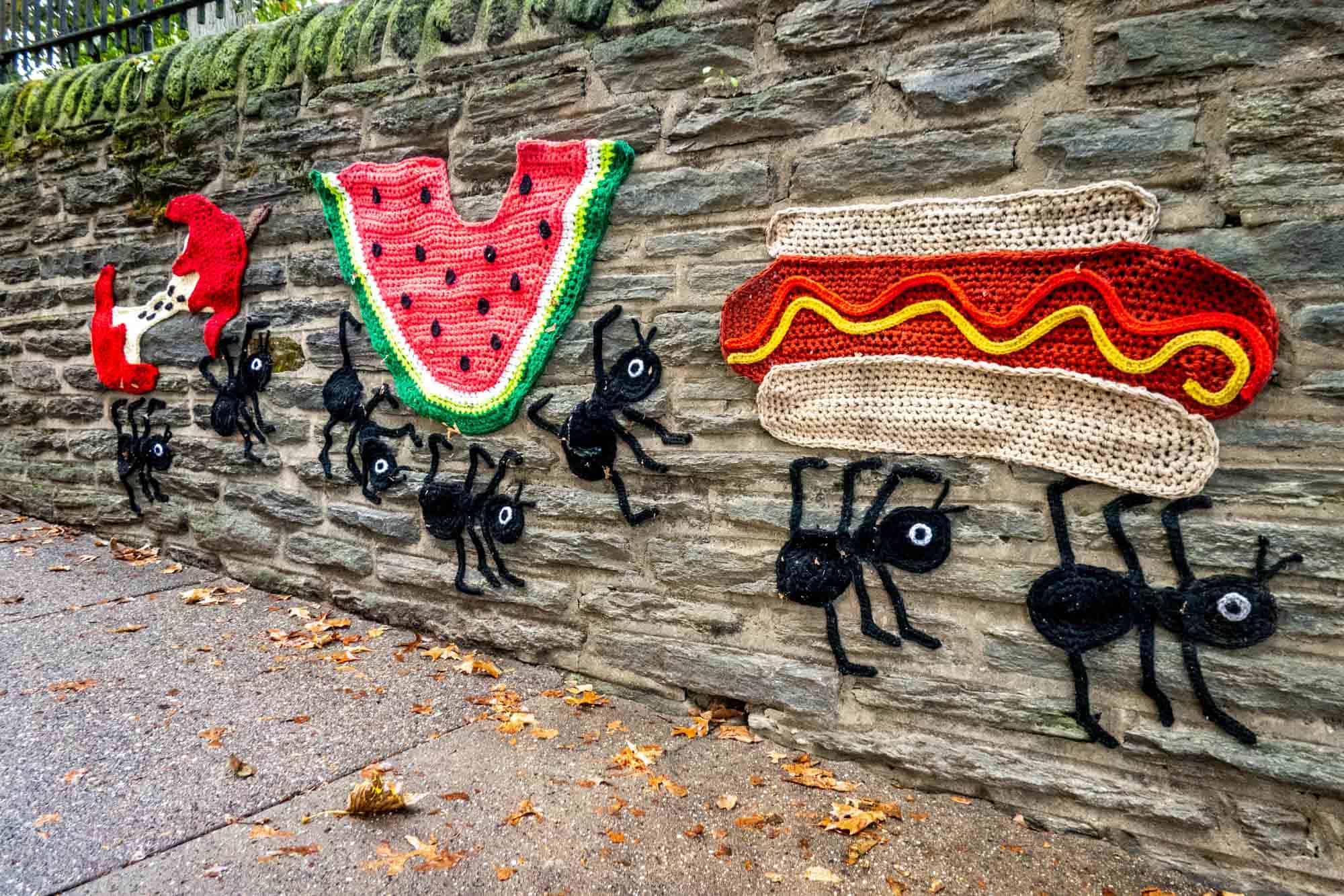 Yarn bomb by Nicole Nikolich (Lace in the Moon) of ants carrying off an apple, watermelon and hot dog from a picnic 