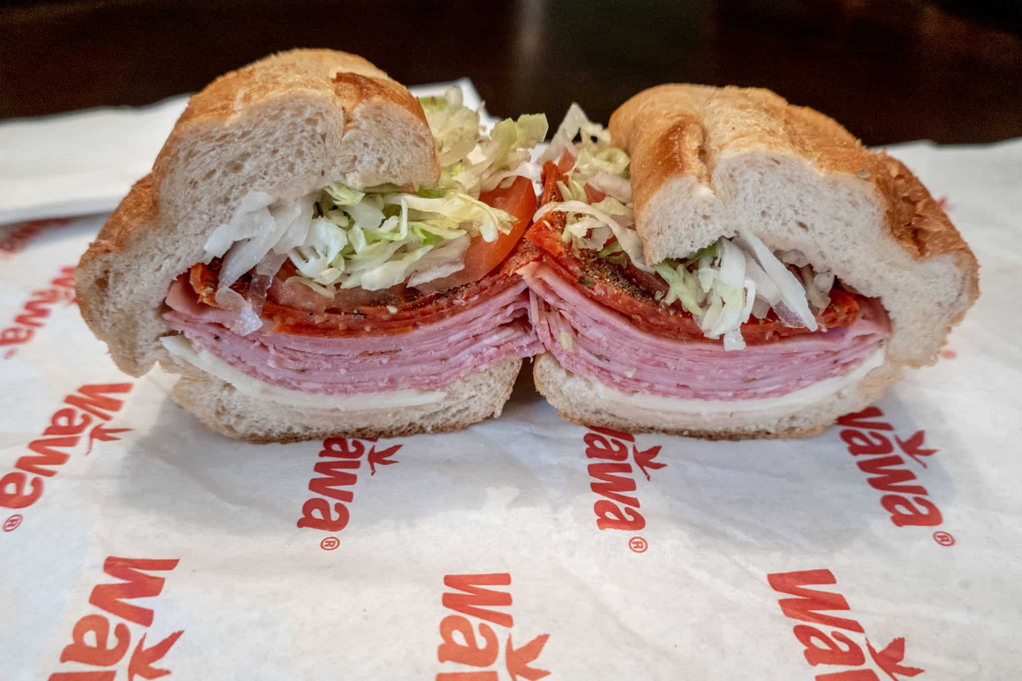 Italian hoagie sandwich with cold cuts, lettuce, and tomato on a Wawa wrapper.