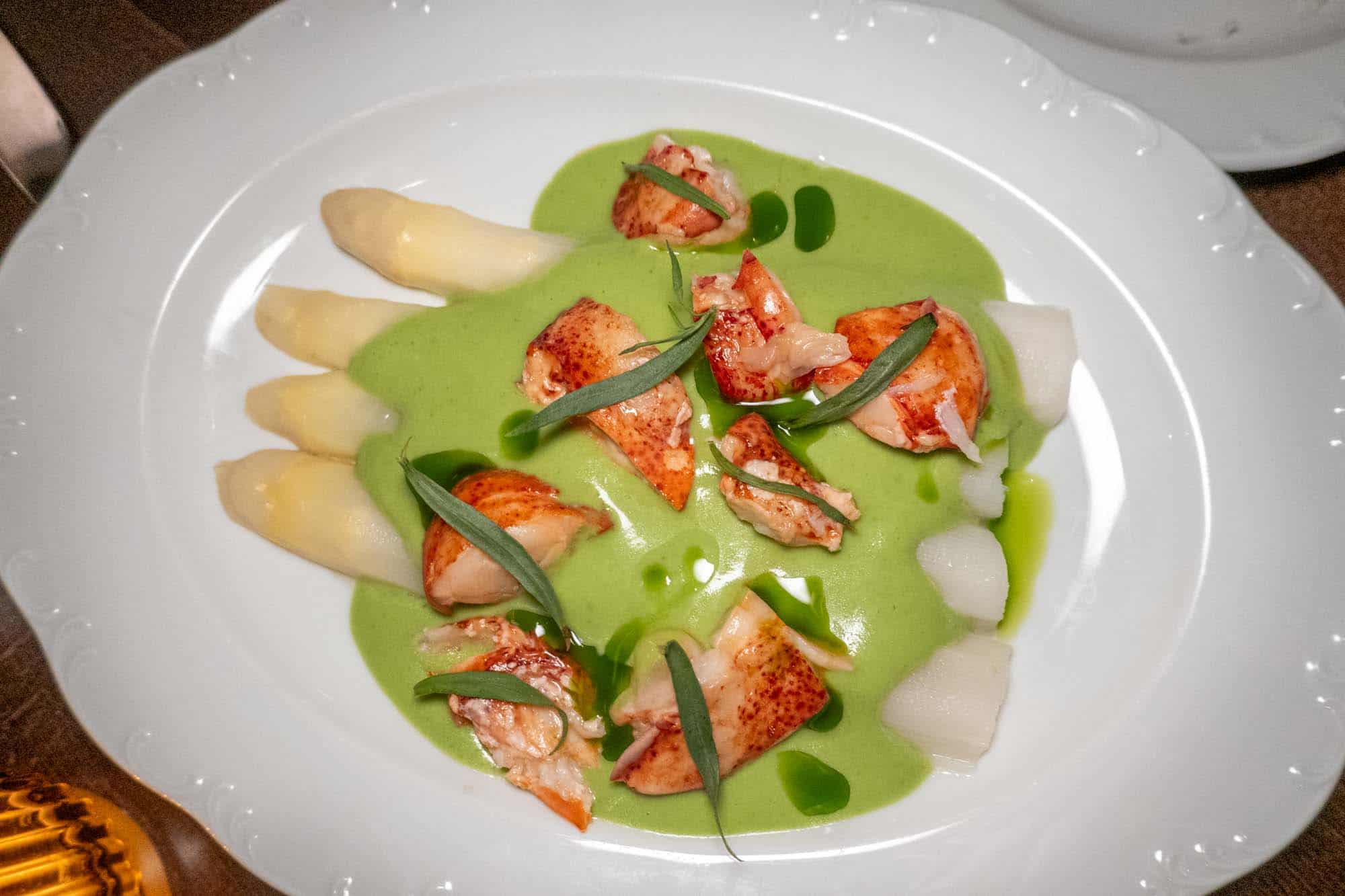 White asparagus topped with lovage sauce and lobster pieces