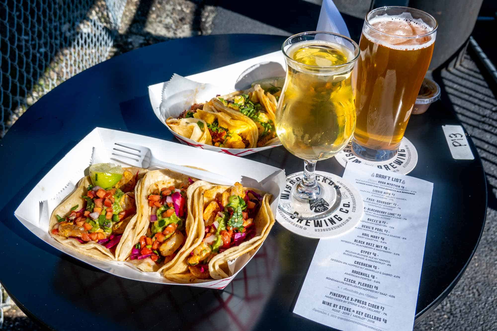 Trays of tacos on a table with two beers