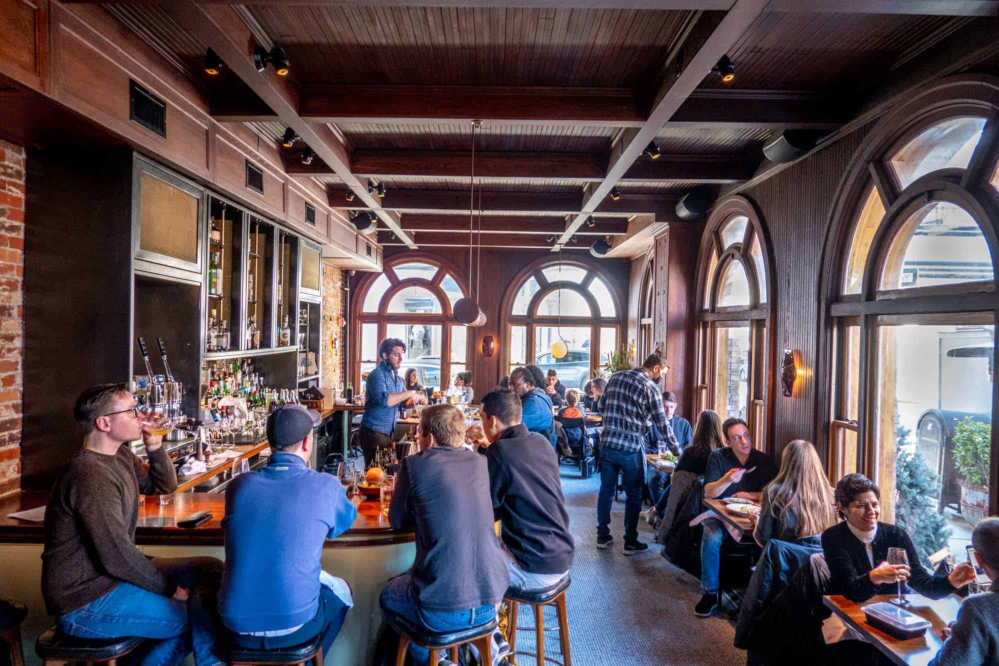 People sitting at a bar in a window-filled room with lots of natural light.