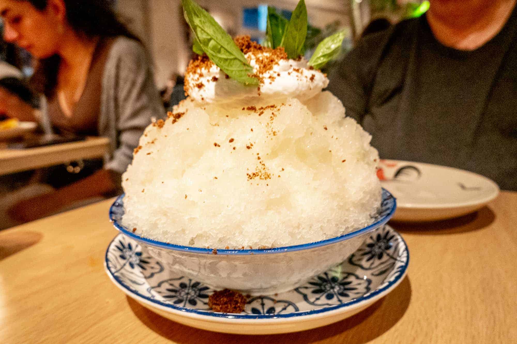 Shaved ice toped with cream and basil leaves.