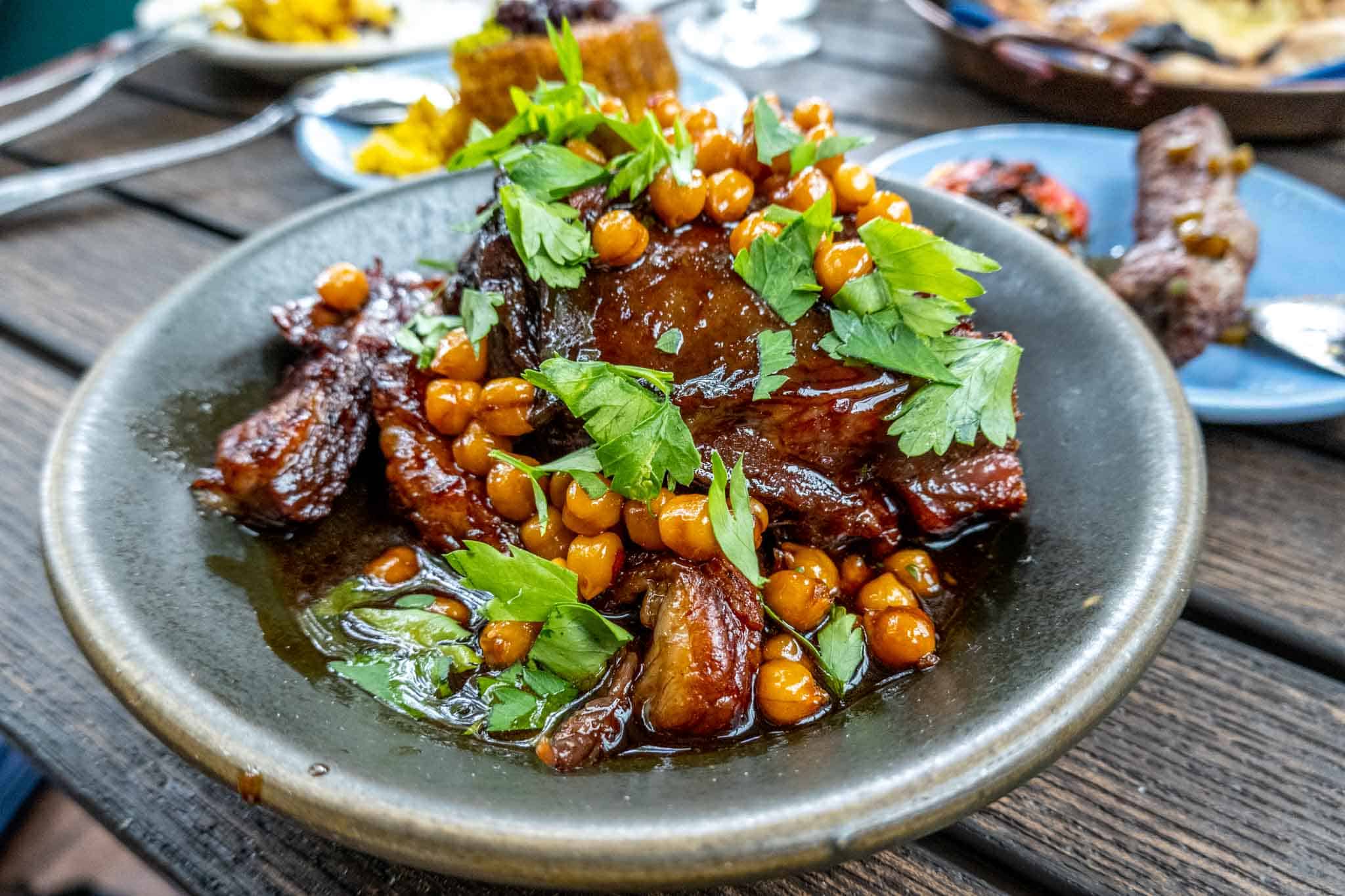 Roasted lamb topped with chickpeas and cilantro in a bowl.