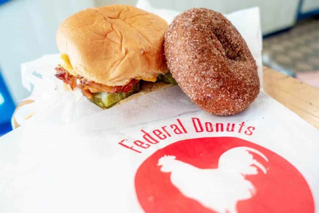 Fried chicken sandwich and a donut on a Federal Donuts bag, one of the best places to eat in Philly