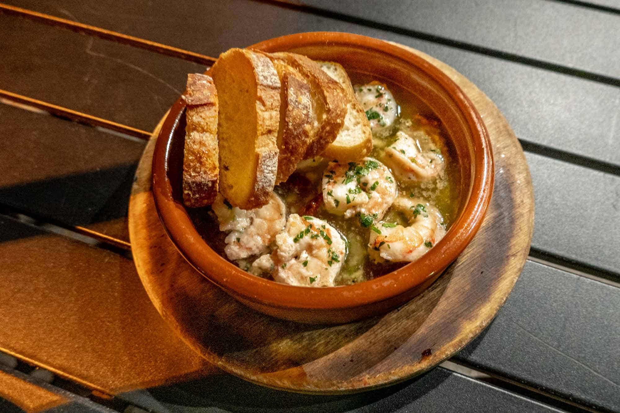 Shrimp in a dish with garlic butter sauce and bread slices.