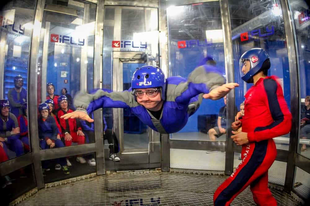 Man indoor skydiving with people watching